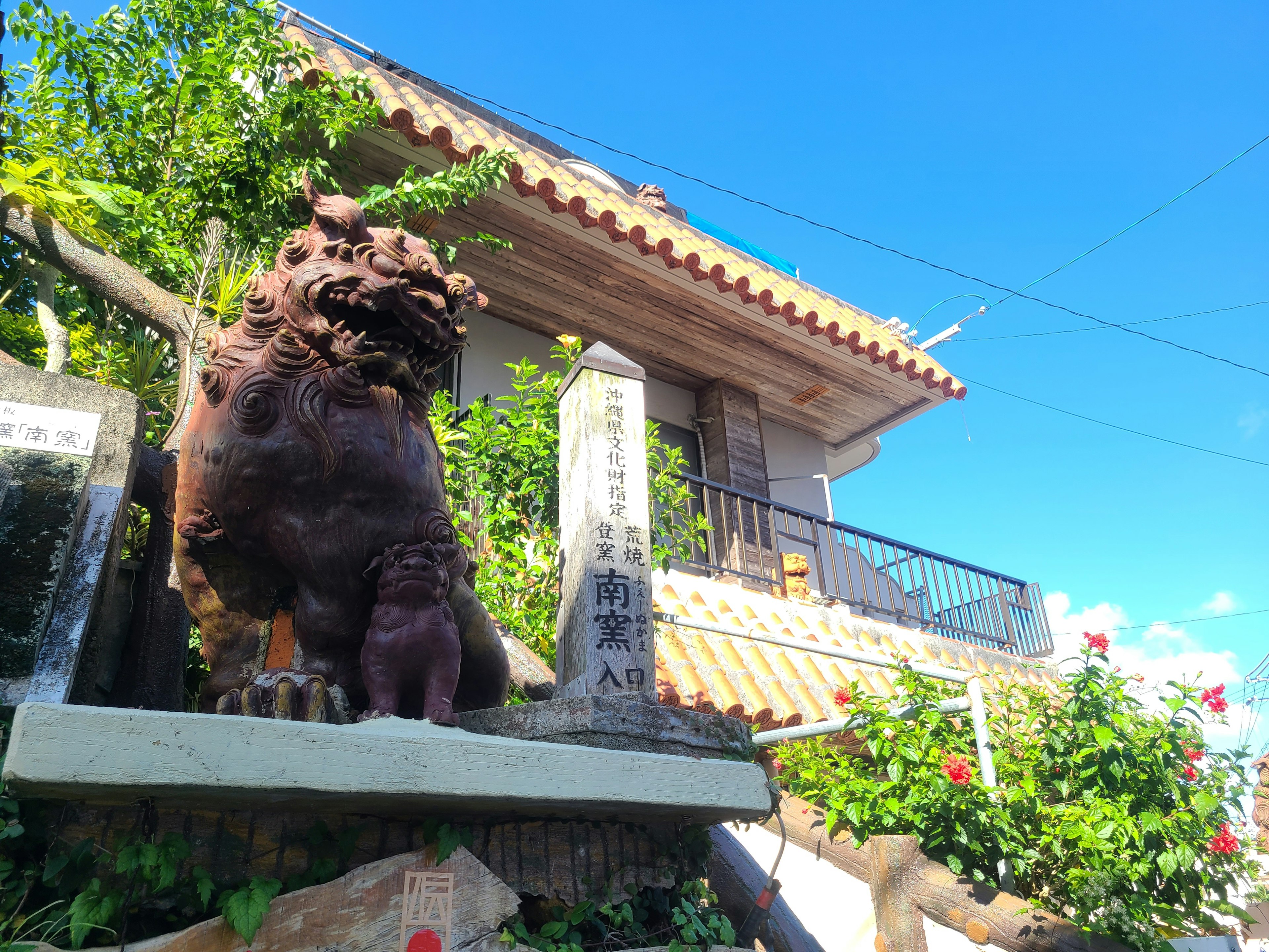 Estatua de Shisa frente a una casa con cielo azul