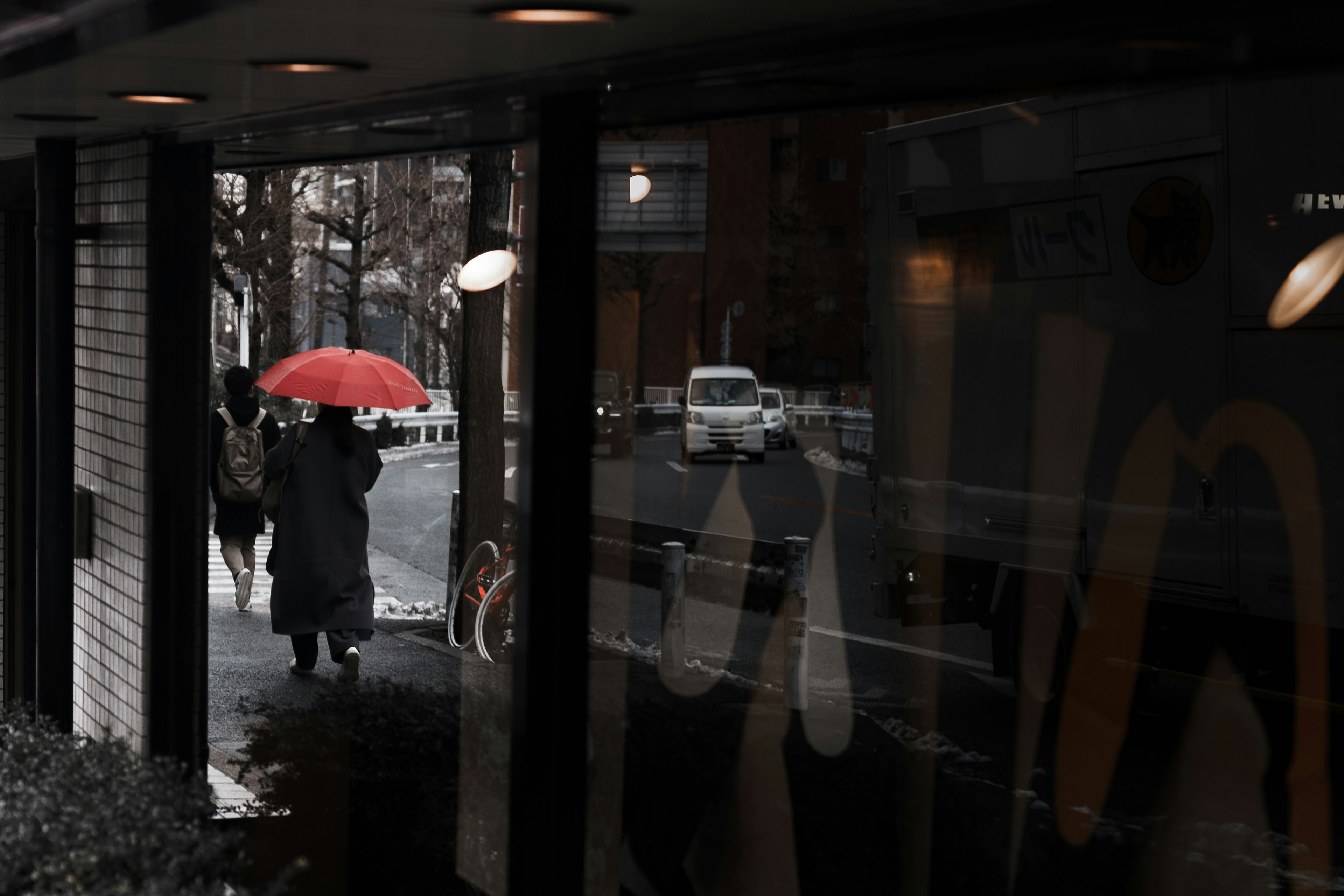 Eine Person, die mit einem roten Regenschirm in einer Stadtszene geht