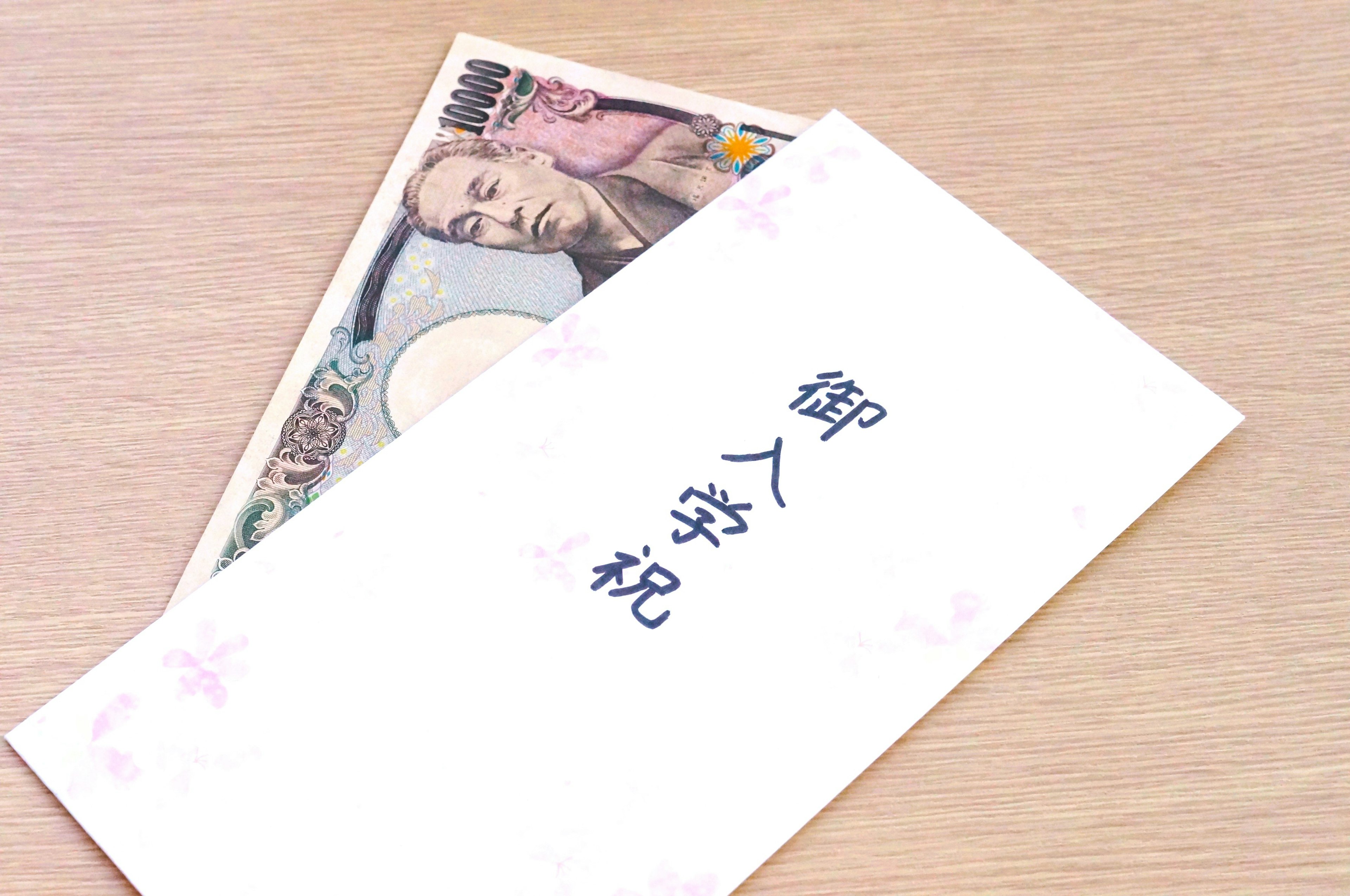 A white envelope containing Japanese yen and the text '御入学祝'