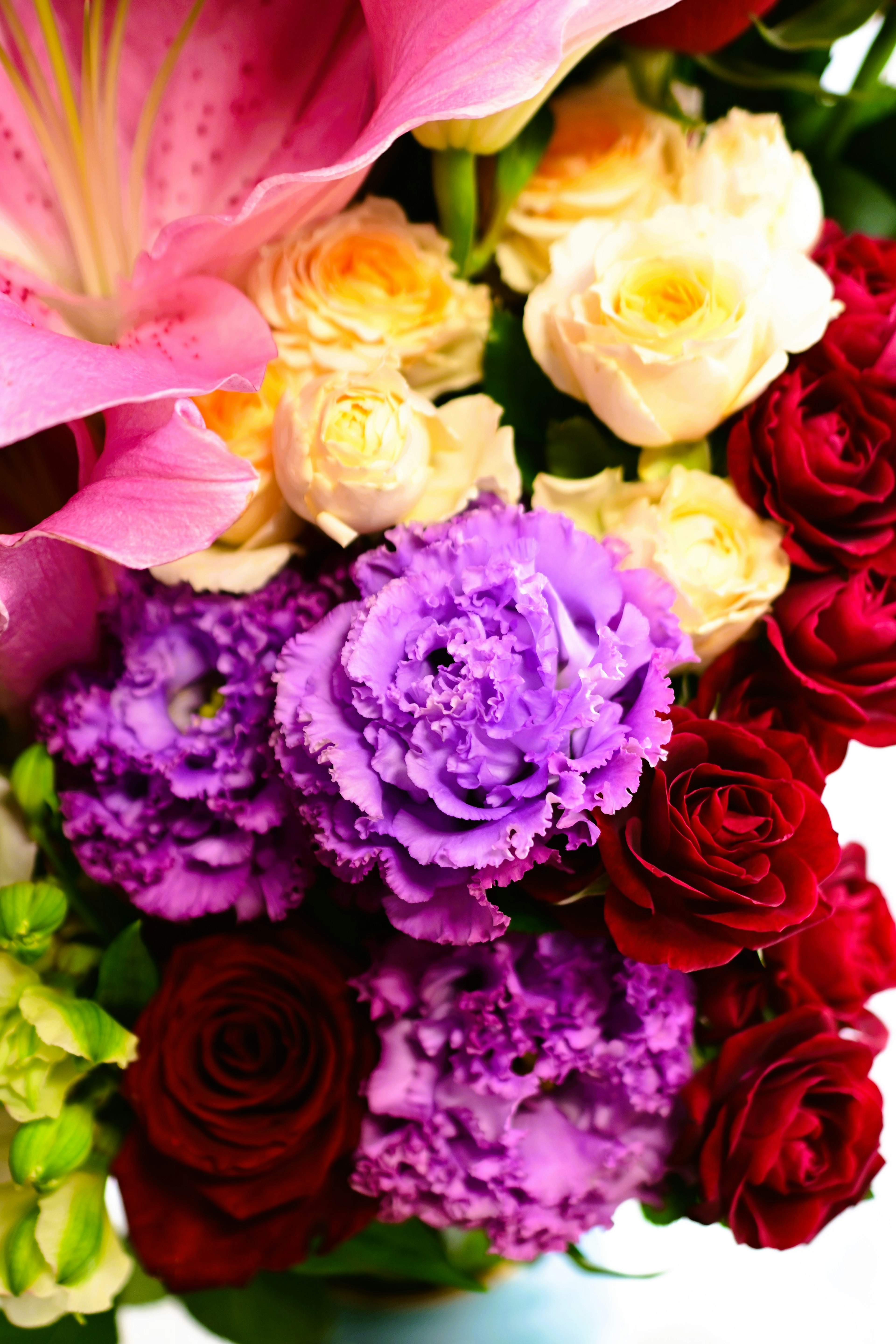 A vibrant bouquet featuring pink lilies yellow roses red roses and purple flowers