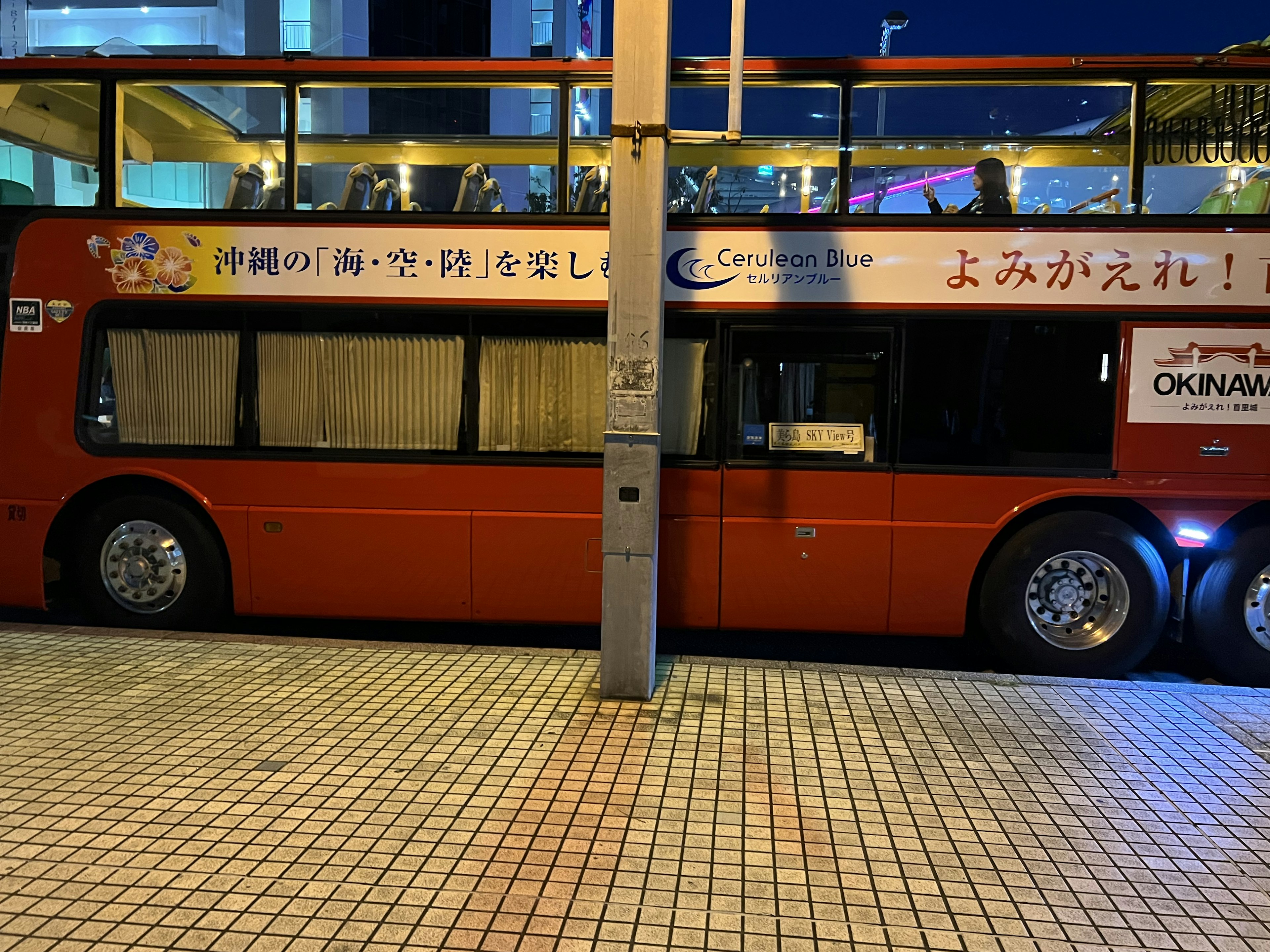 Seitenansicht eines roten Doppeldeckerbusses, der in der Nachtstadt geparkt ist