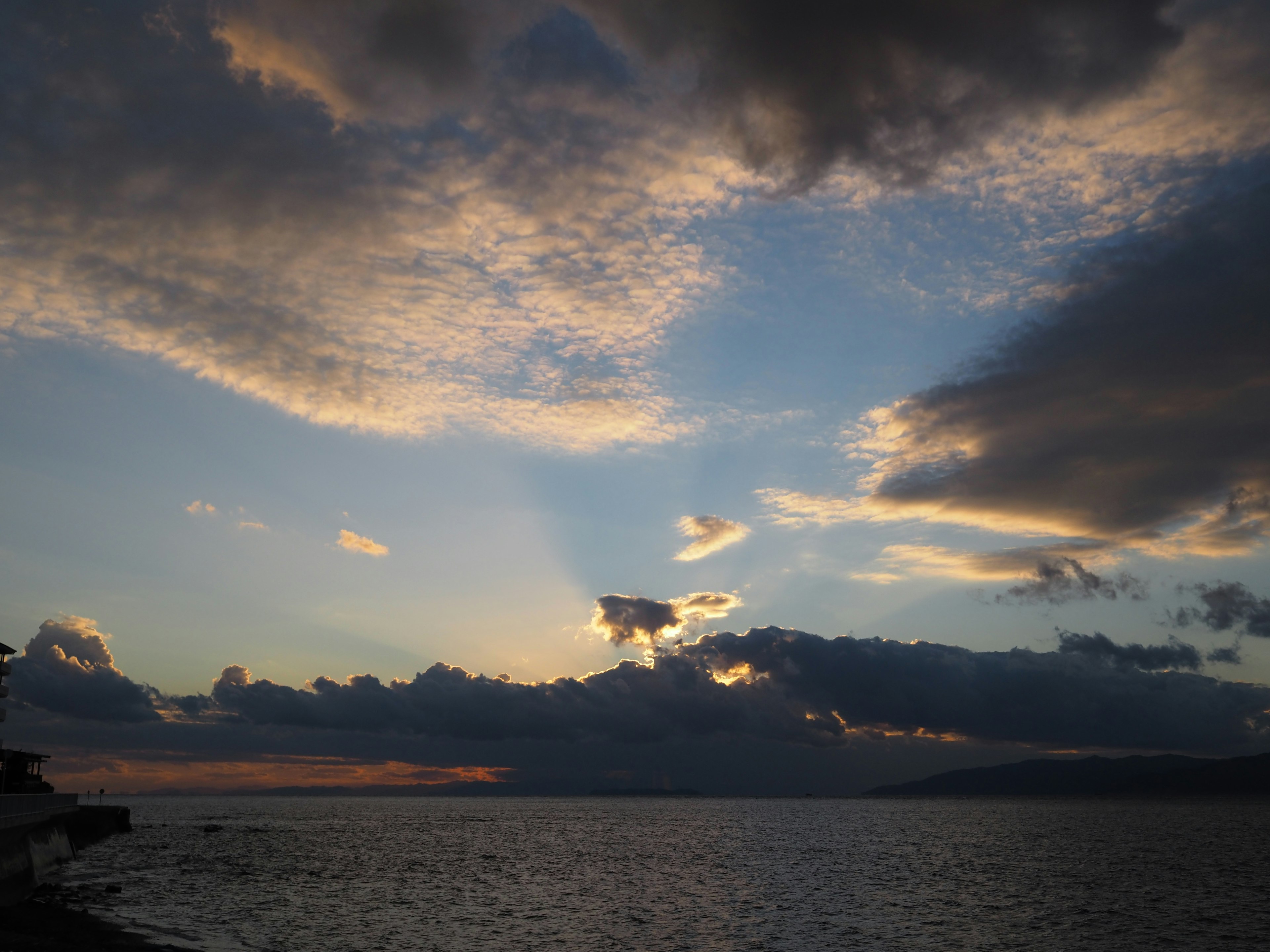 Scenic view of a sunset sky over the ocean with dramatic clouds and rays of light