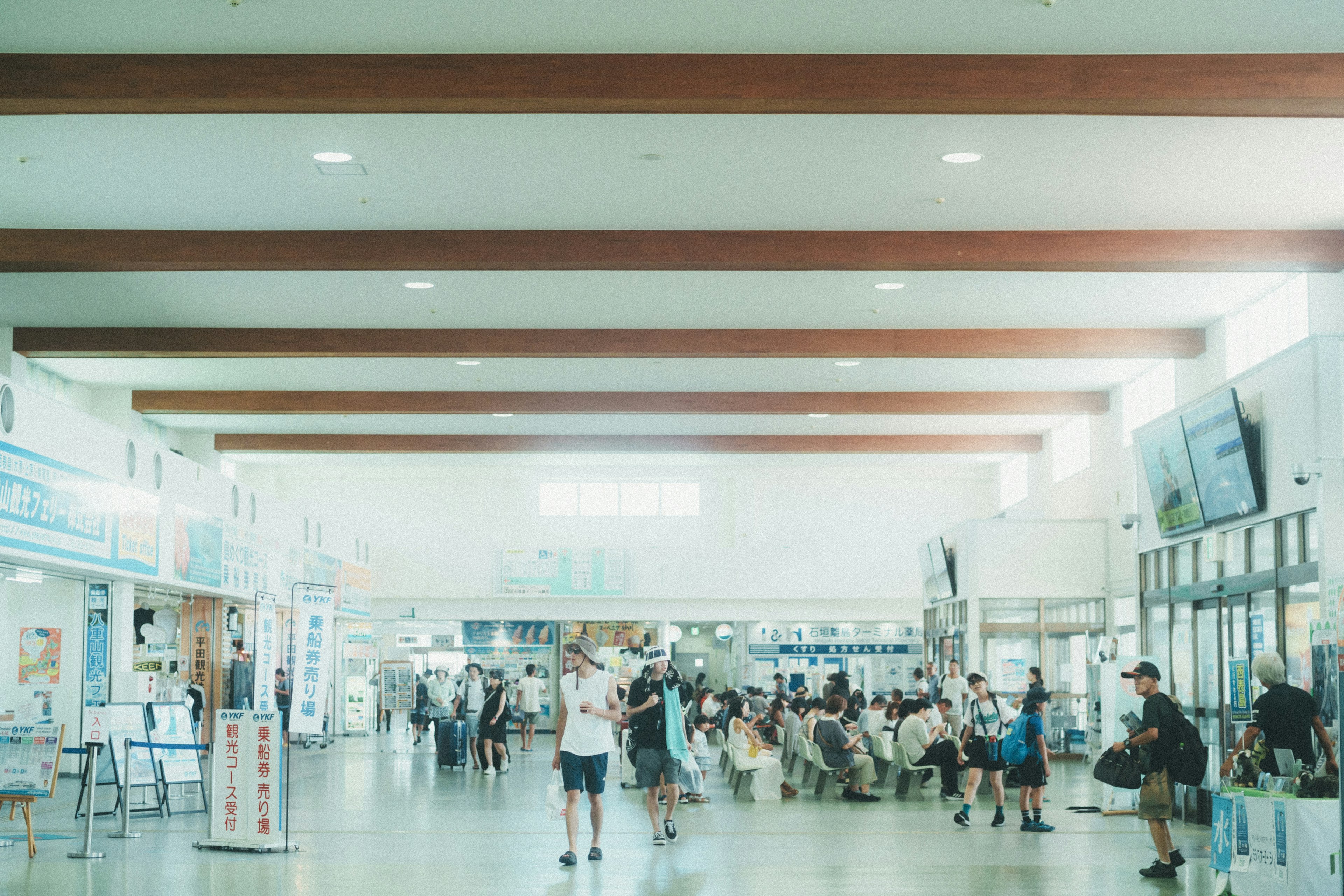 明るい空間で人々が行き交う駅の内部の風景