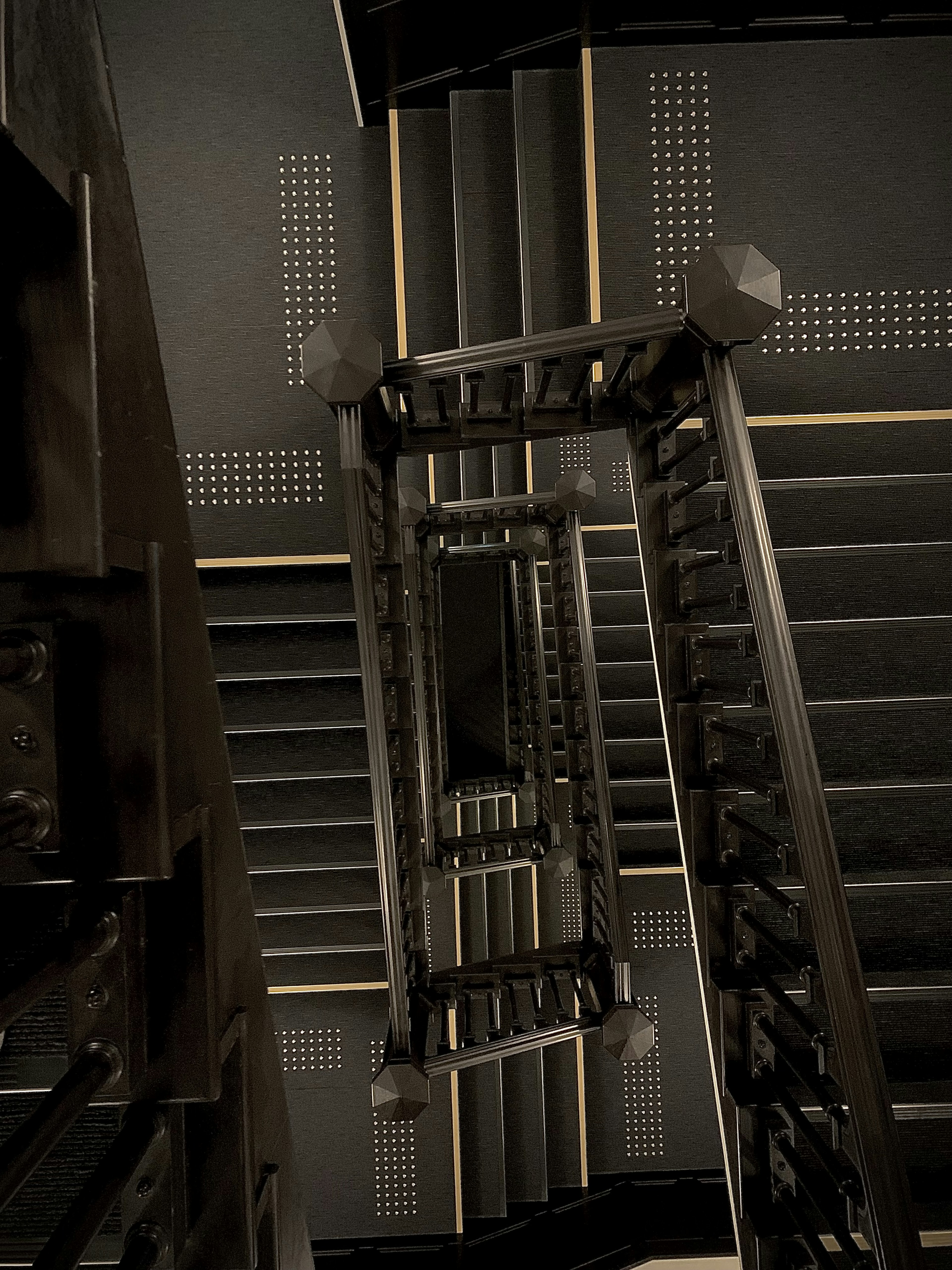 View from above of a staircase featuring black railings and unique step design