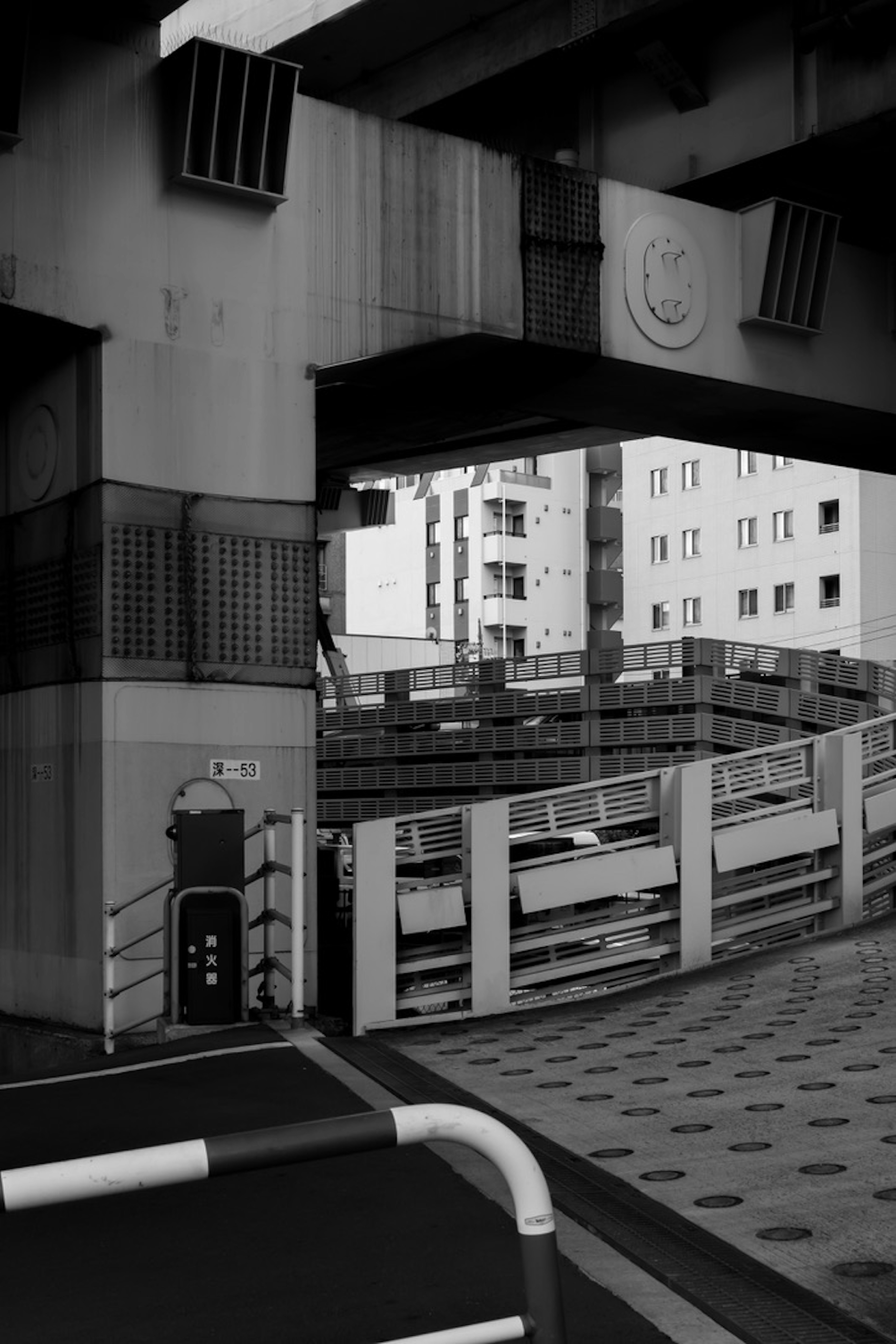 Black and white urban scene with an overpass parking structure visible buildings in the background