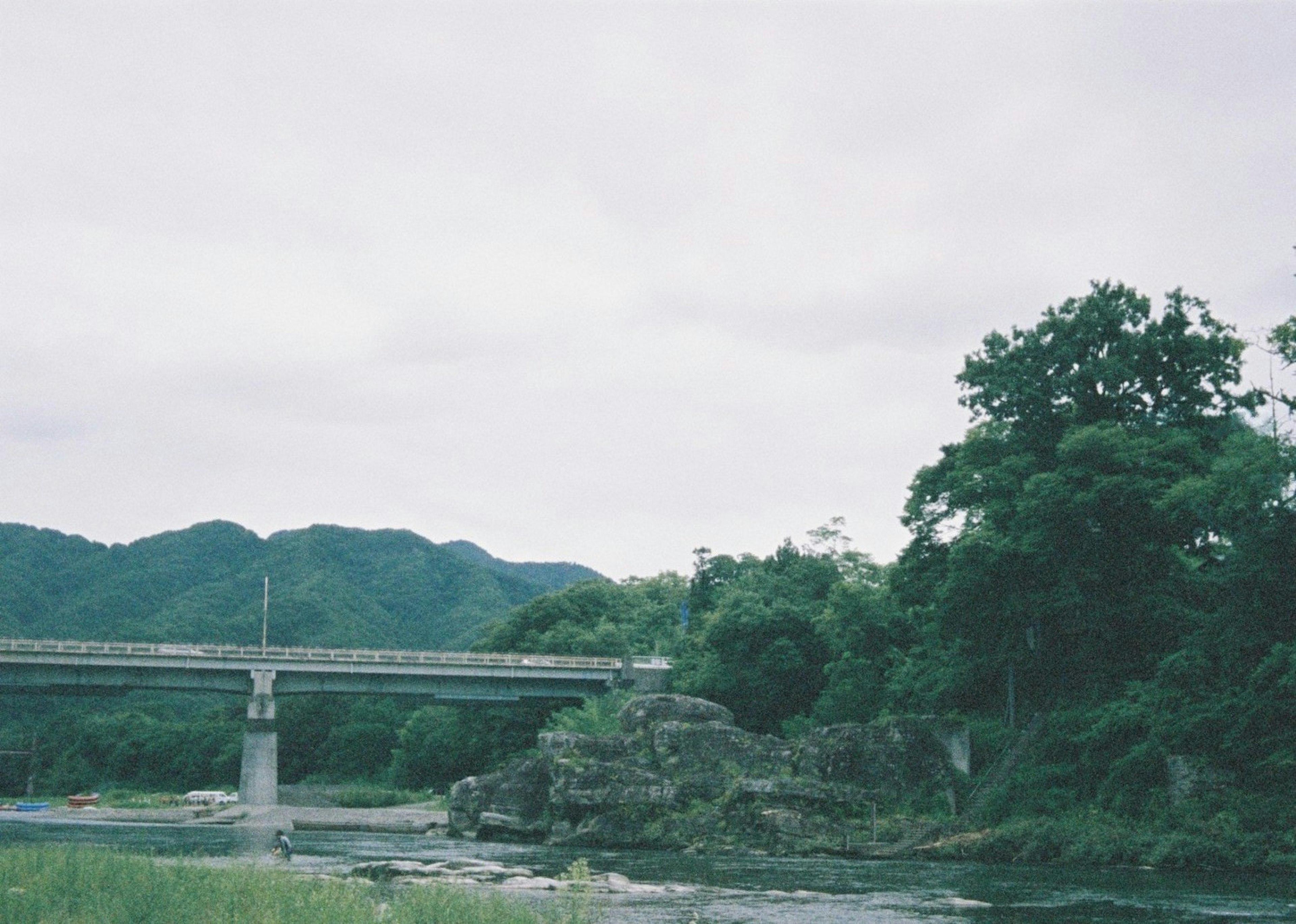 山々に囲まれた川の近くに架かる橋と緑豊かな木々