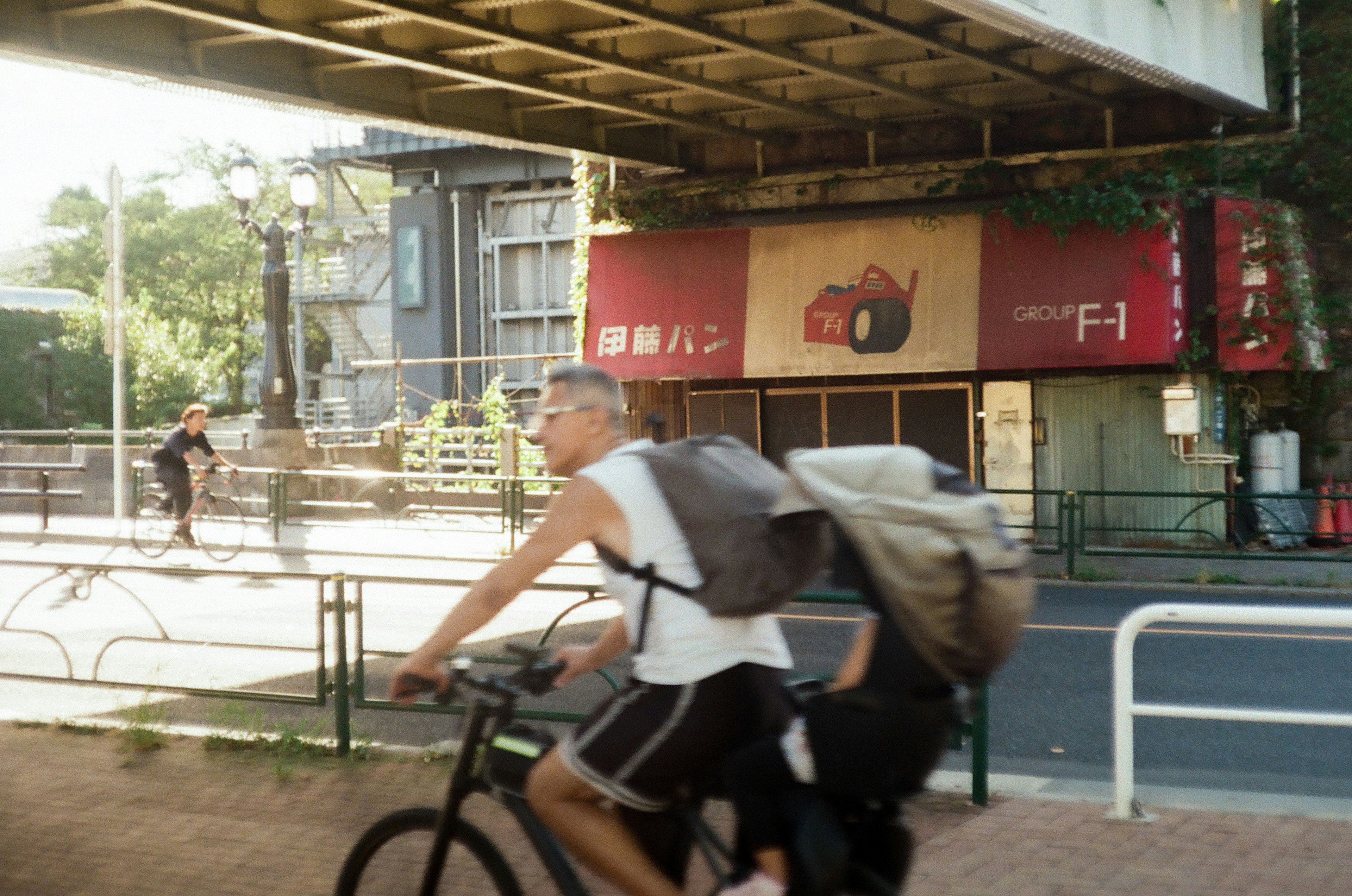 A man riding a bicycle with a backpack against an urban backdrop featuring an advertisement