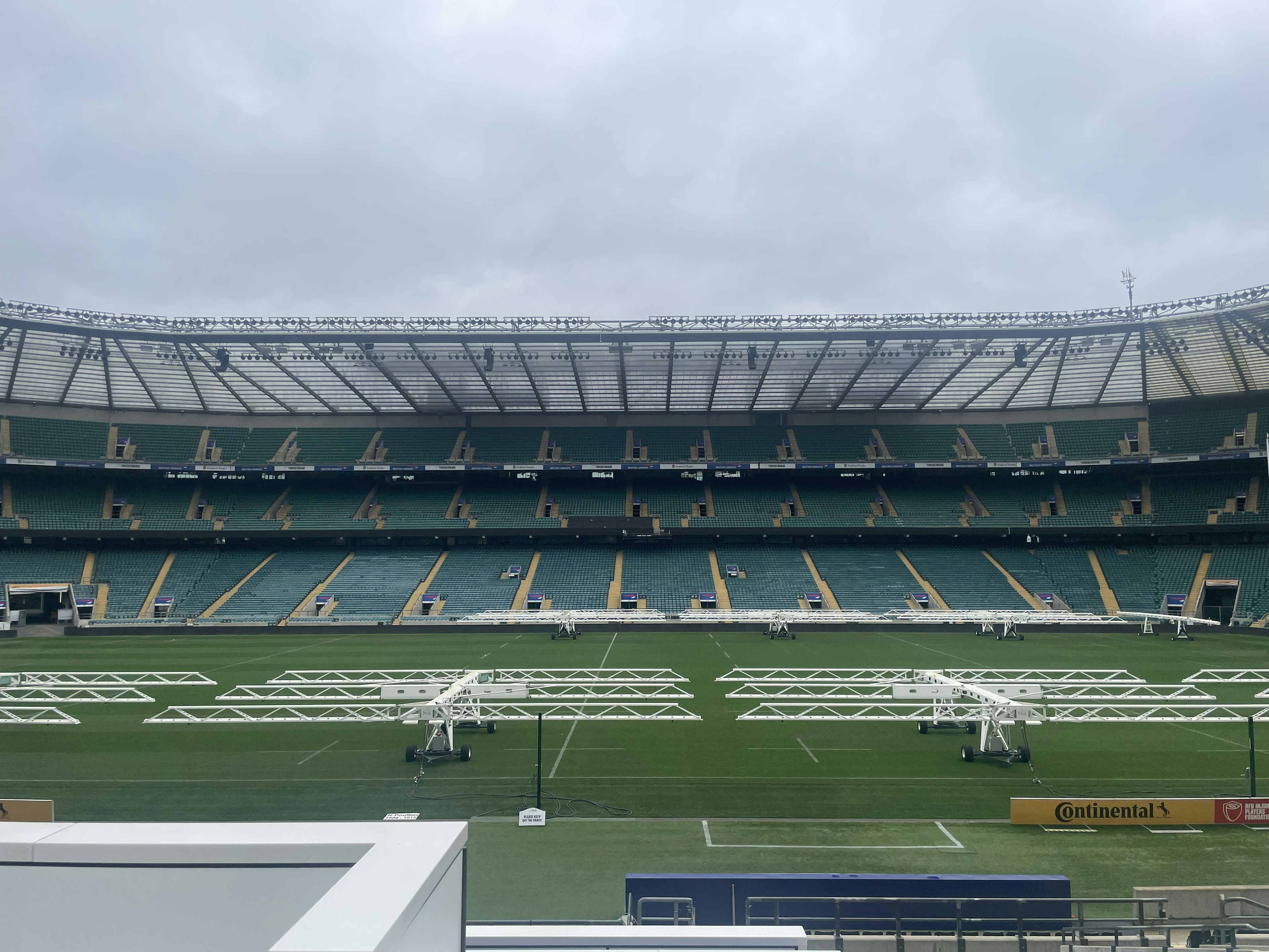 Interior stadion kosong dengan lapangan hijau dan deretan kursi