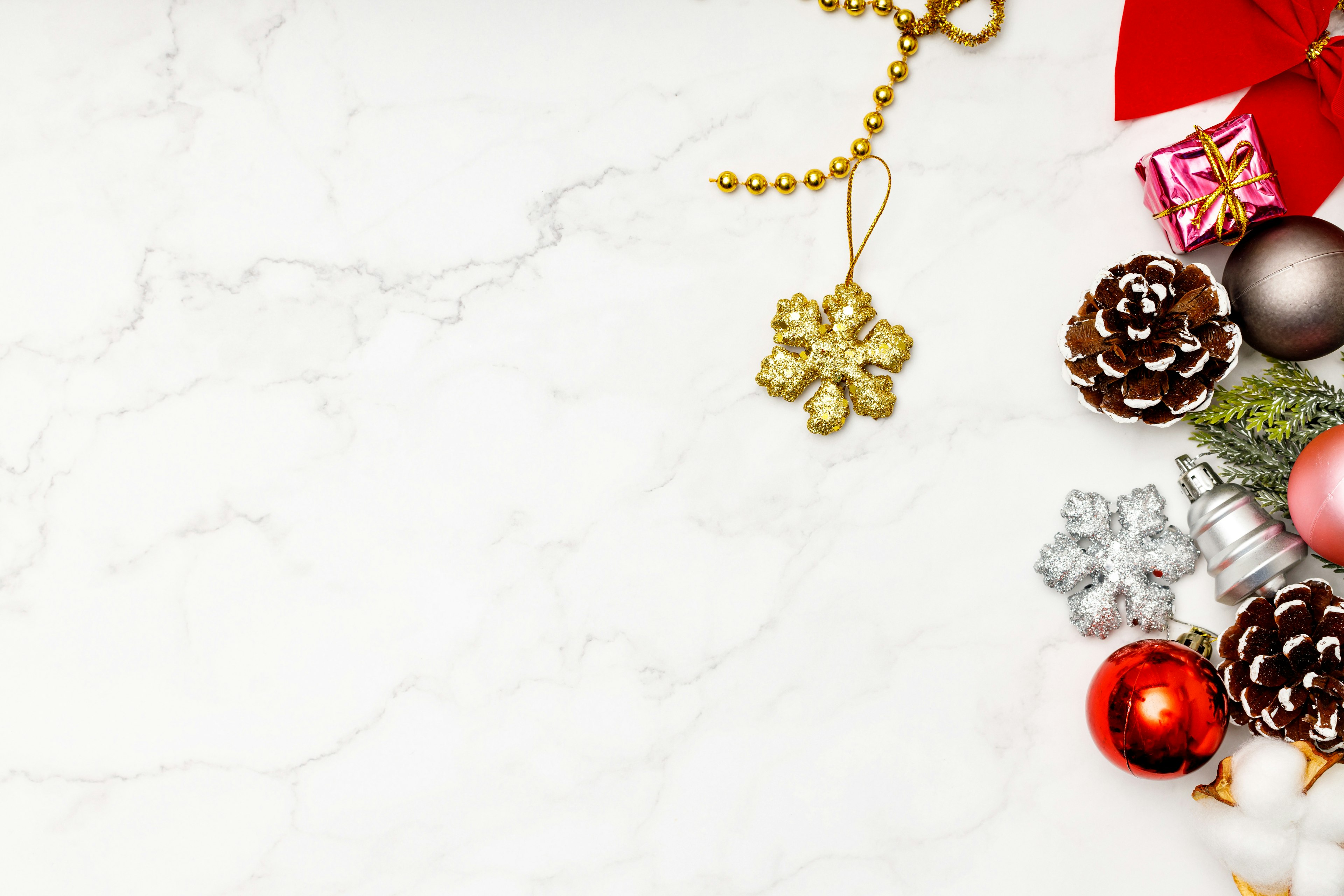 Christmas decorations and pine cones arranged on a white marble background