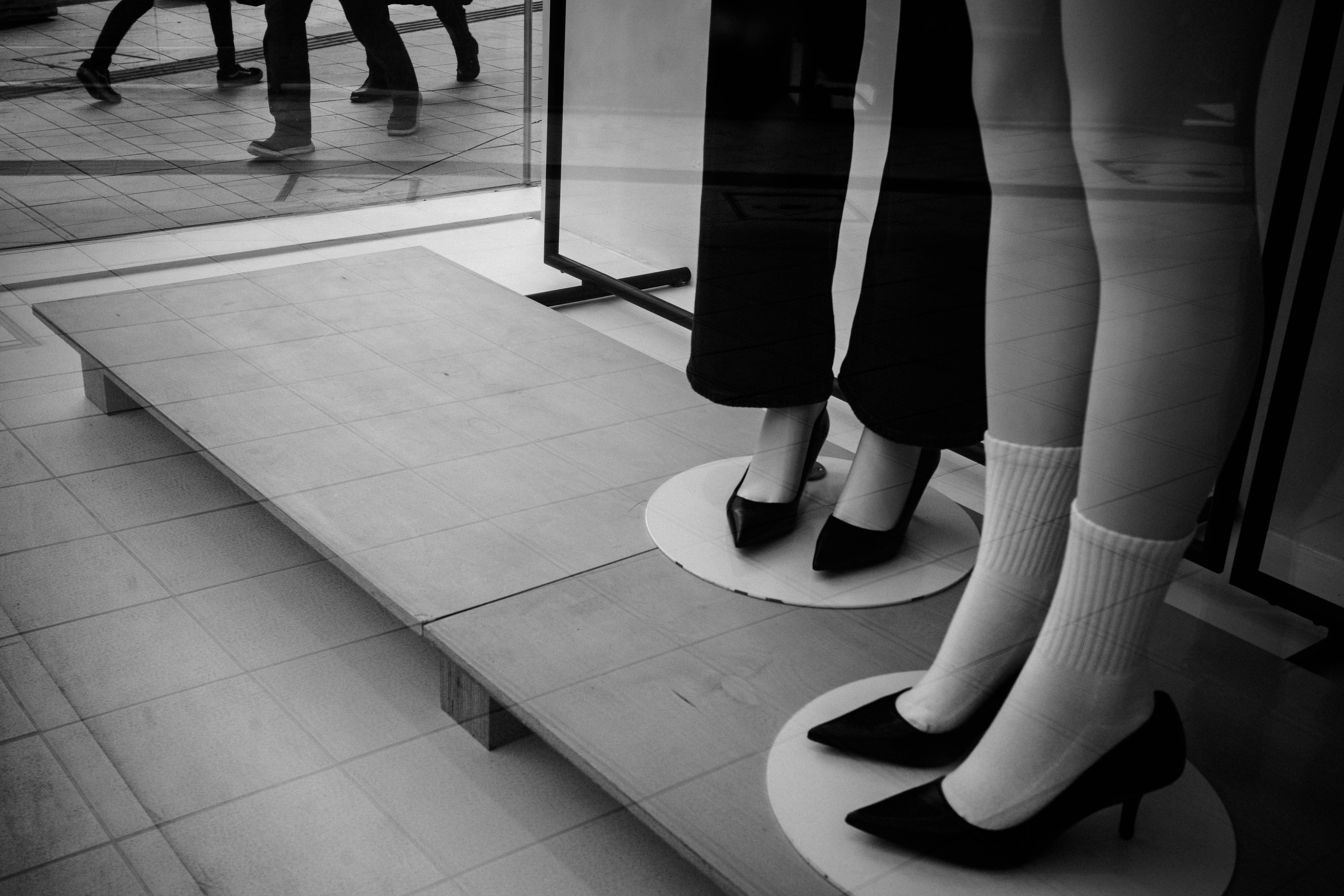 Piernas de maniquí con tacones altos expuestas en una vitrina en blanco y negro