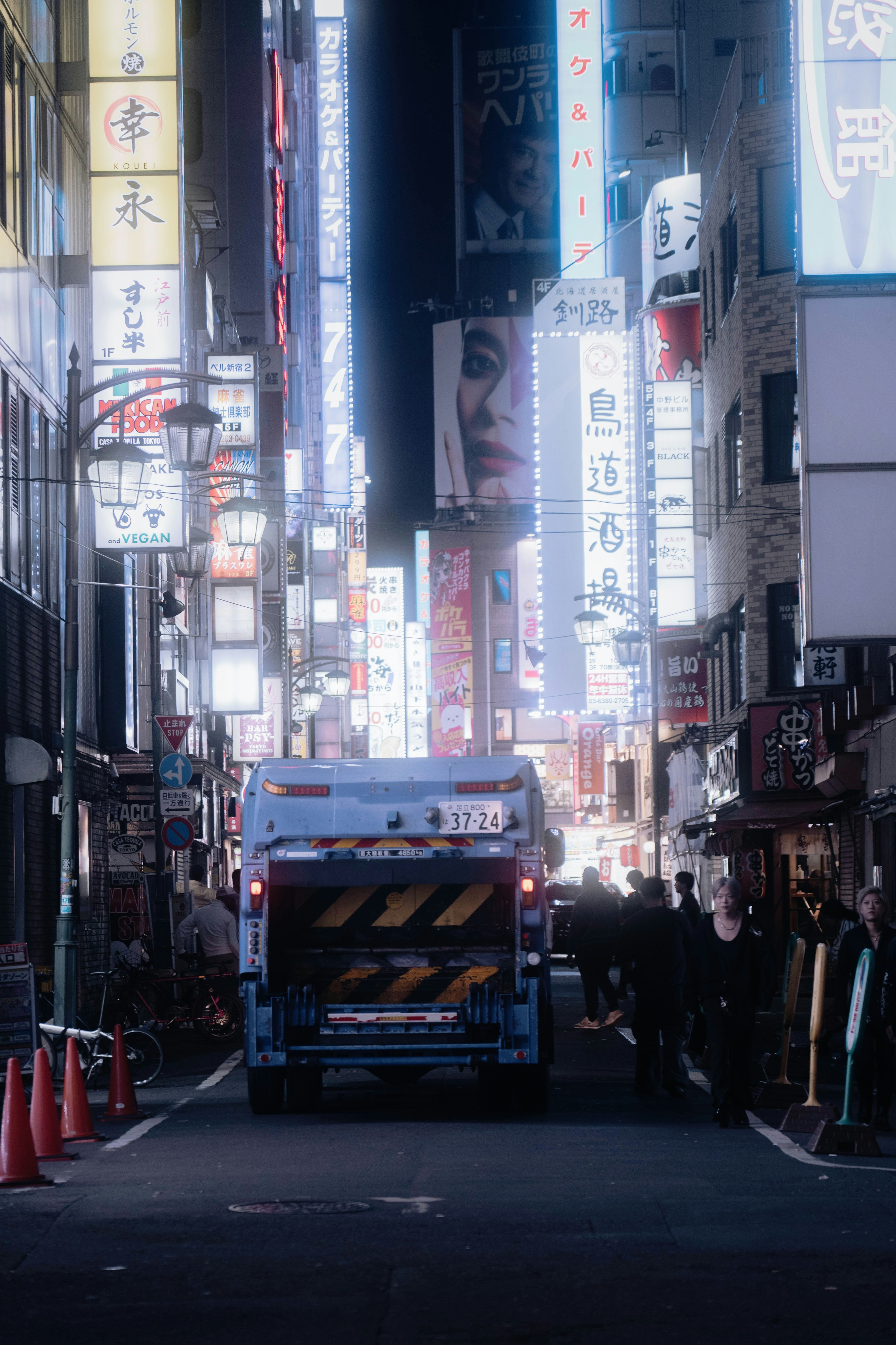 Garbage truck parked on a neon-lit street