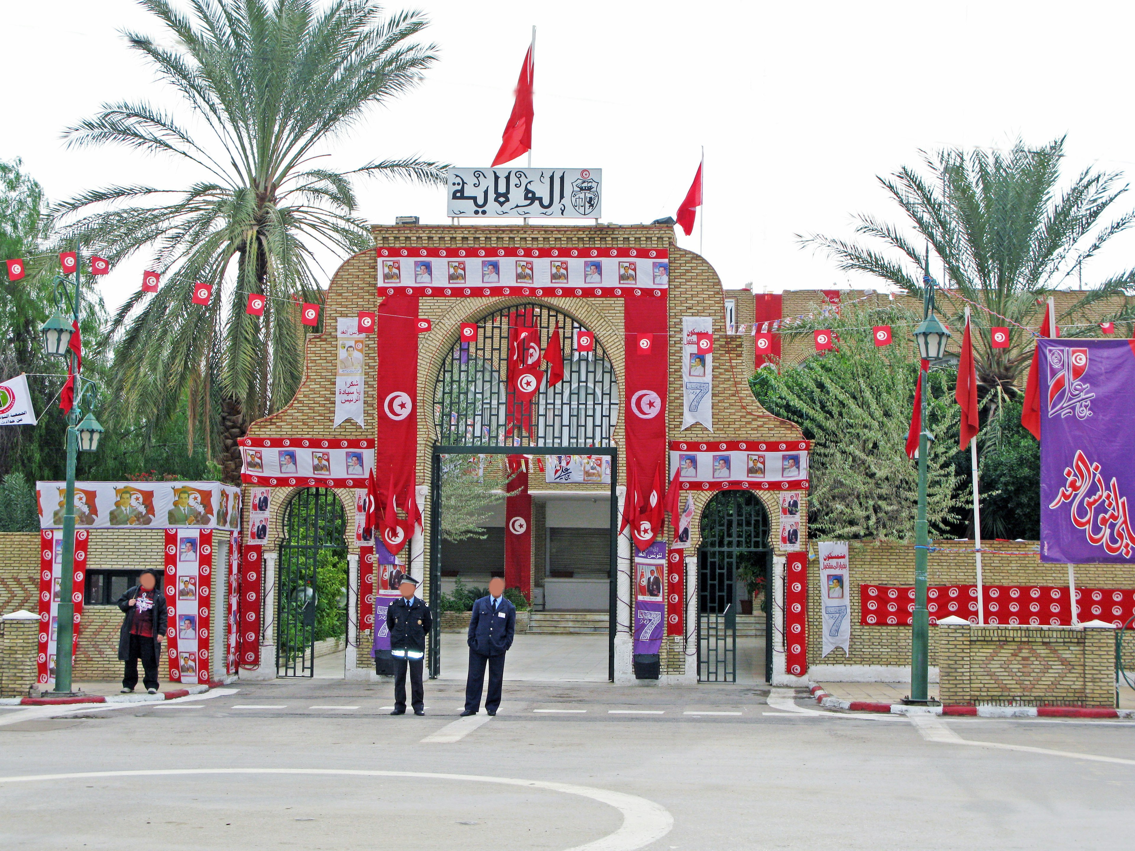 Portail d'entrée orné de décorations rouges et de drapeaux avec des gardes