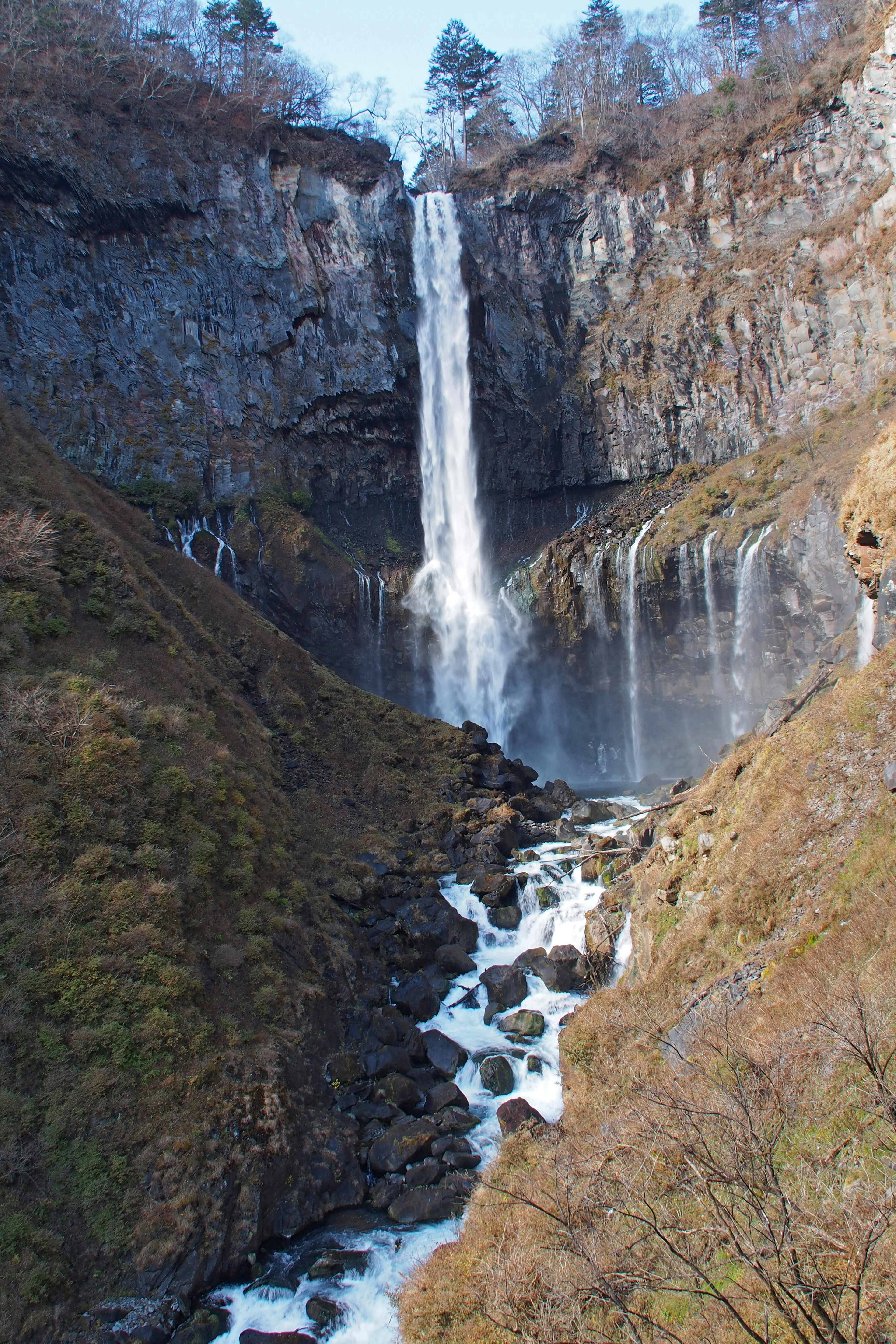 Paesaggio bellissimo con una cascata che scende da scogliere rocciose circondate da vegetazione