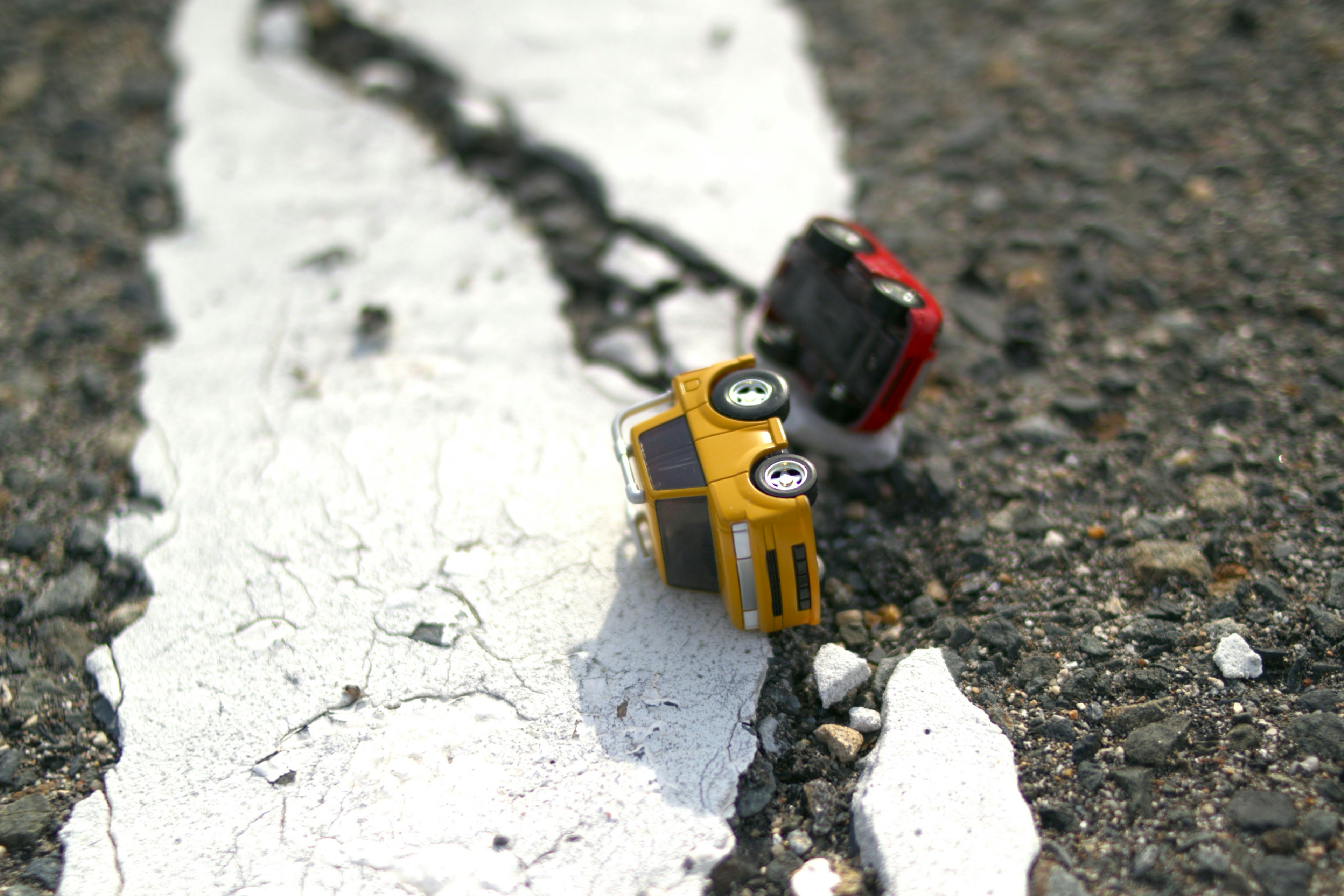 Coche de juguete amarillo y coche de juguete rojo sobre una línea blanca en la carretera