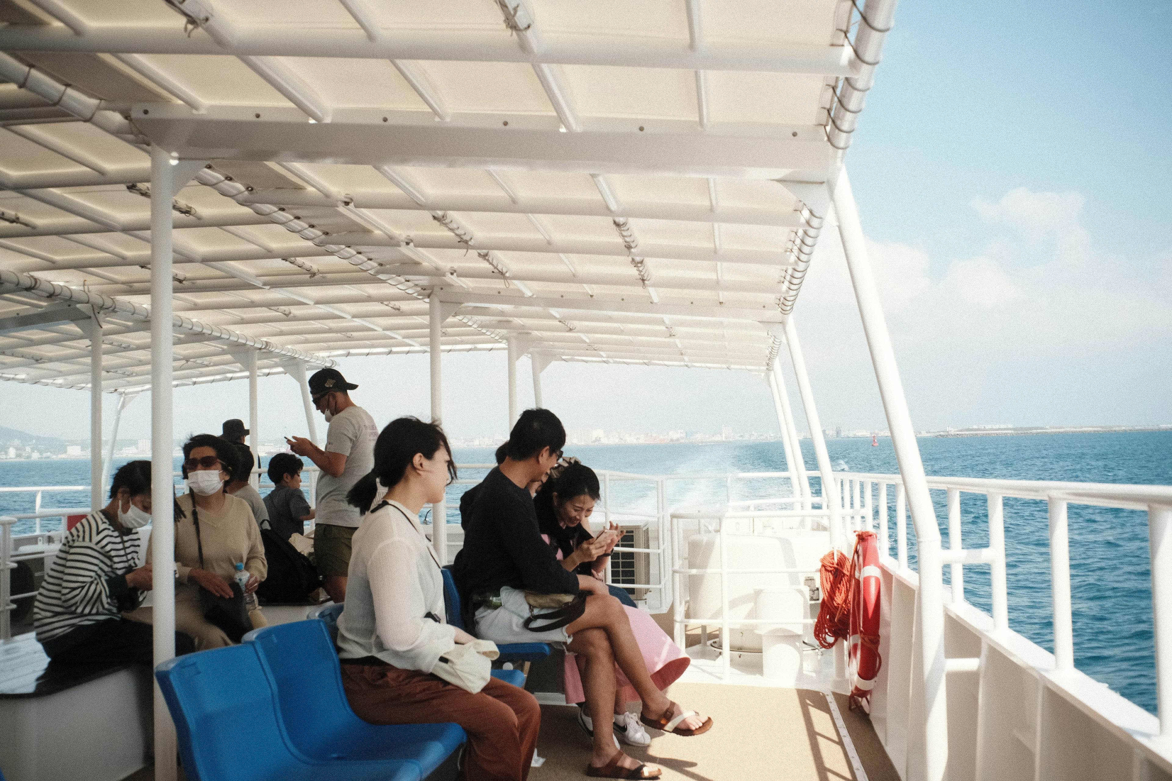 People relaxing on a boat deck with blue seating