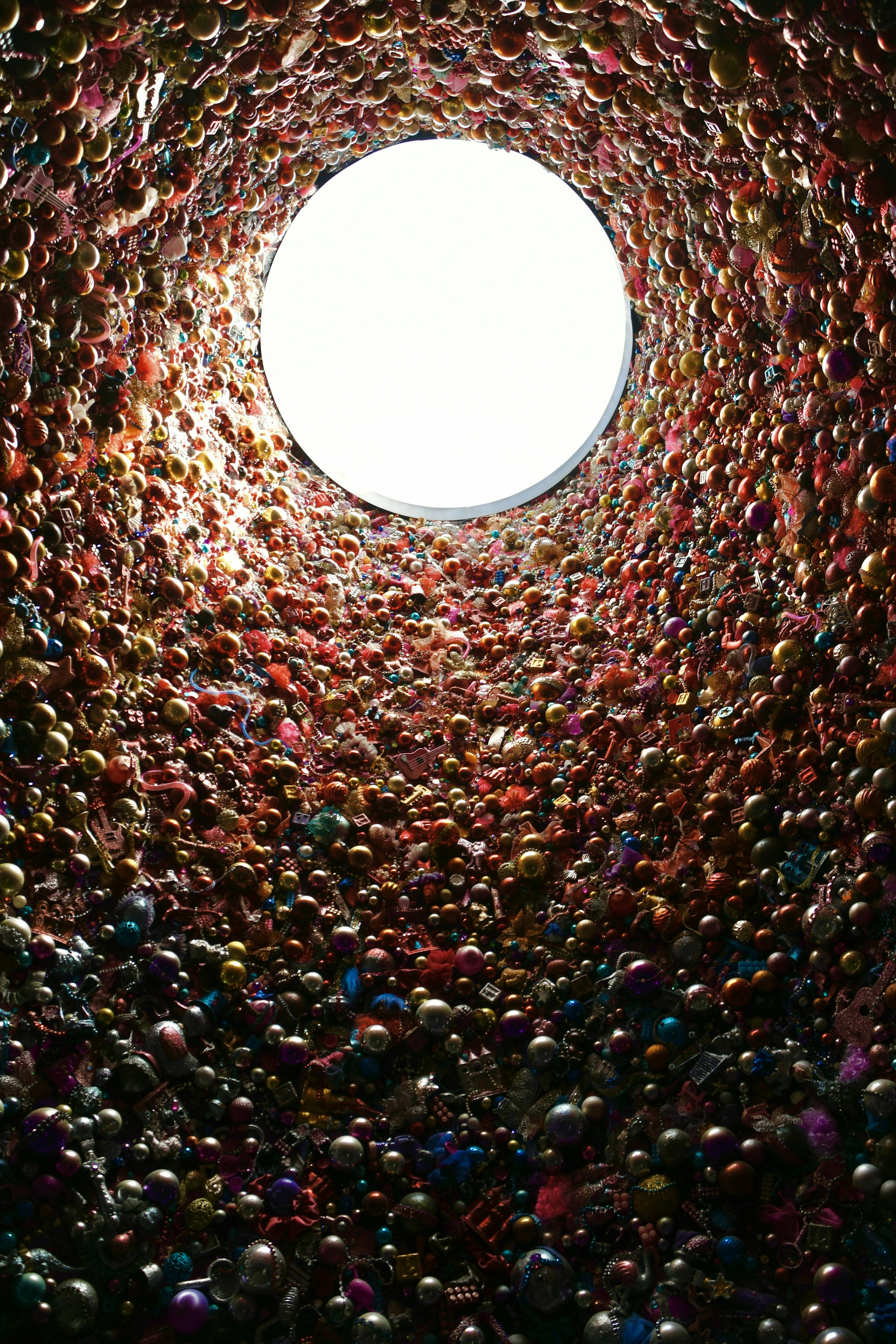 View from inside a tunnel filled with colorful balls looking up at a bright opening