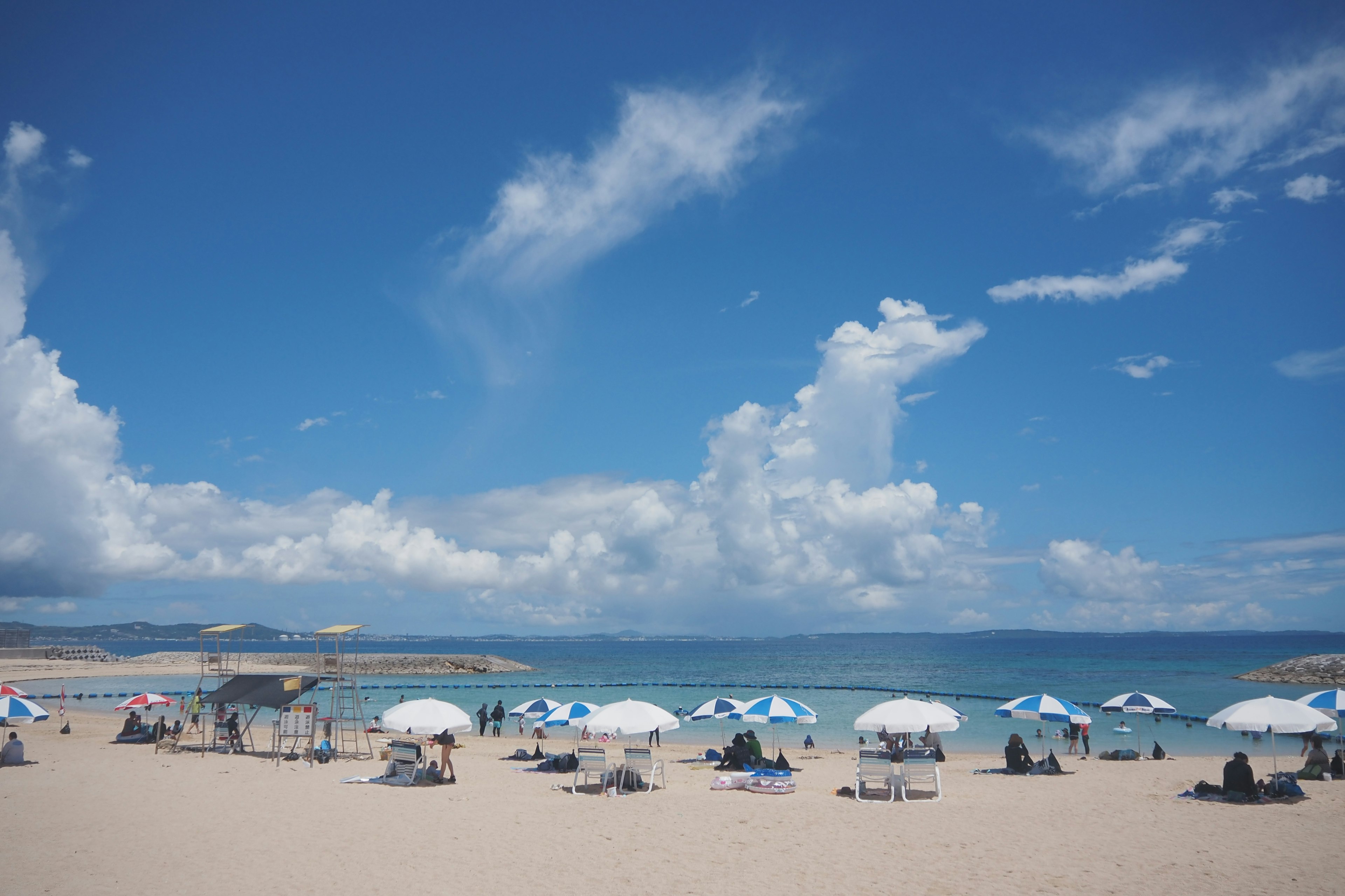 Beach scene with beach umbrellas under a blue sky and white clouds