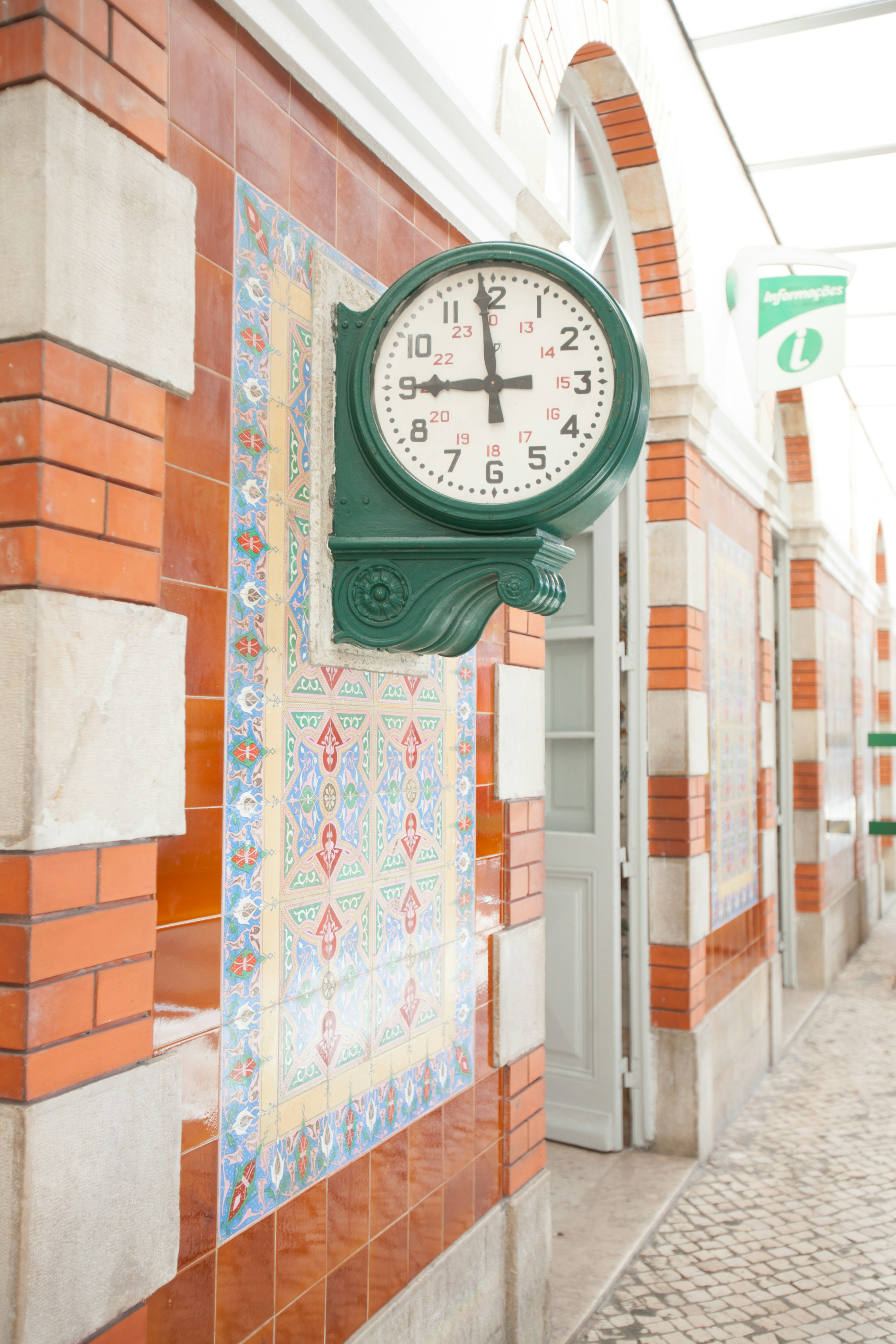 Reloj verde de pared con azulejos decorativos en el exterior de un edificio