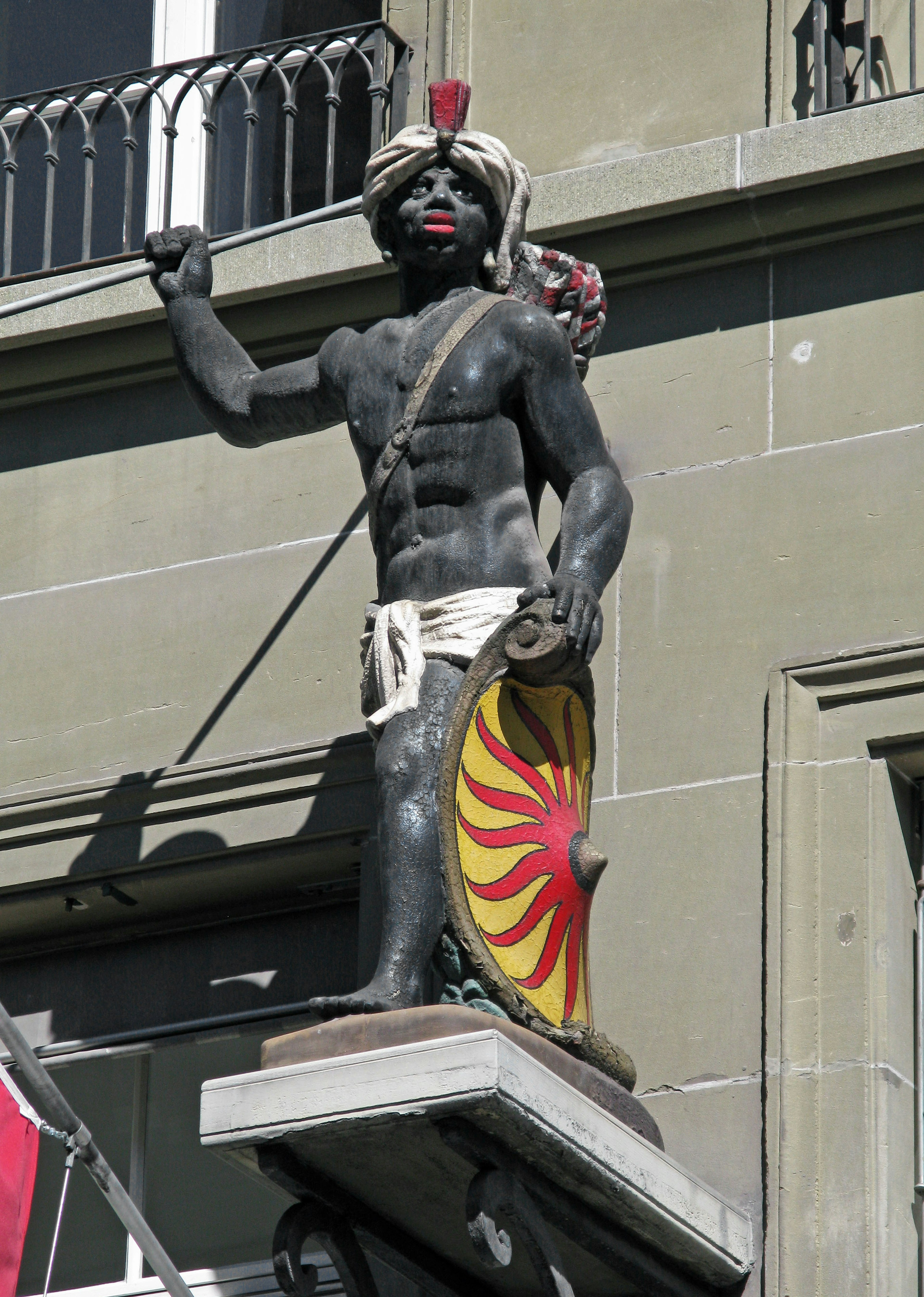 Statue eines Kriegers mit schwarzer Haut, der ein Schild an einer Gebäudefassade hält