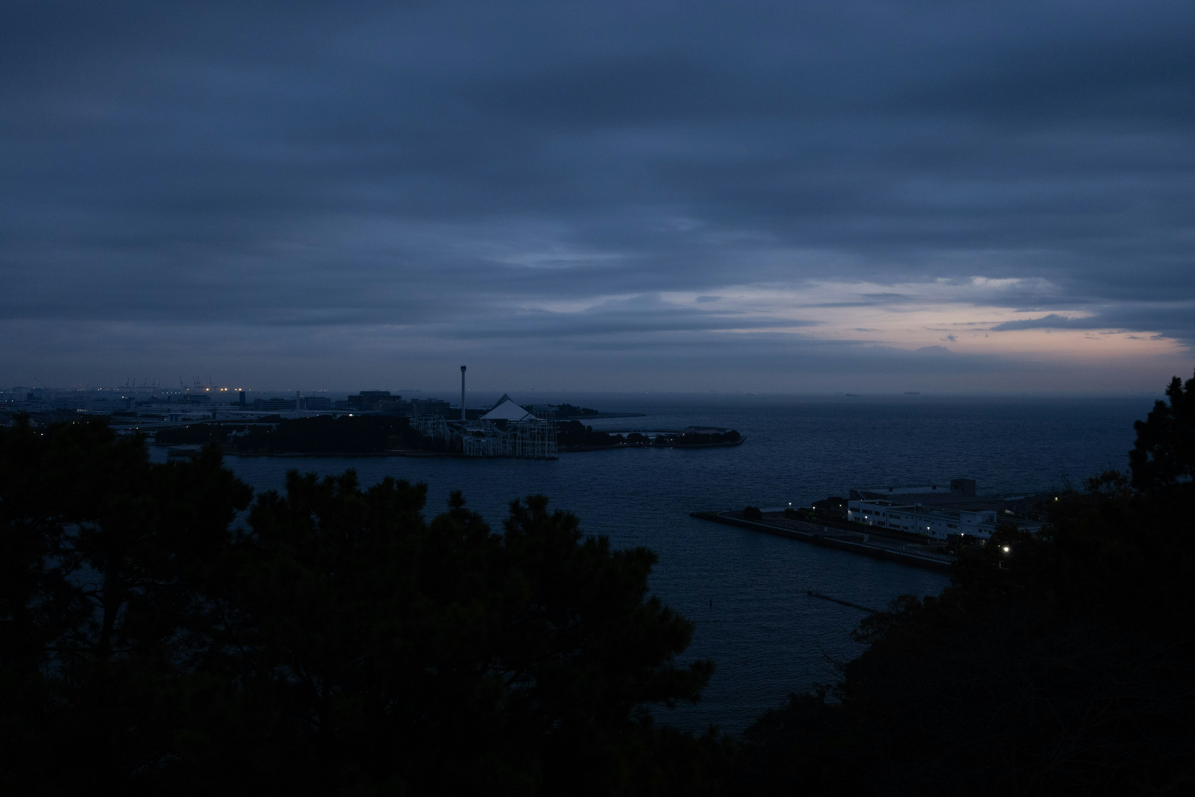 Vue nocturne de la mer et du port Ciel bleu foncé avec des lumières d'horizon faibles Lumières du port éparpillées
