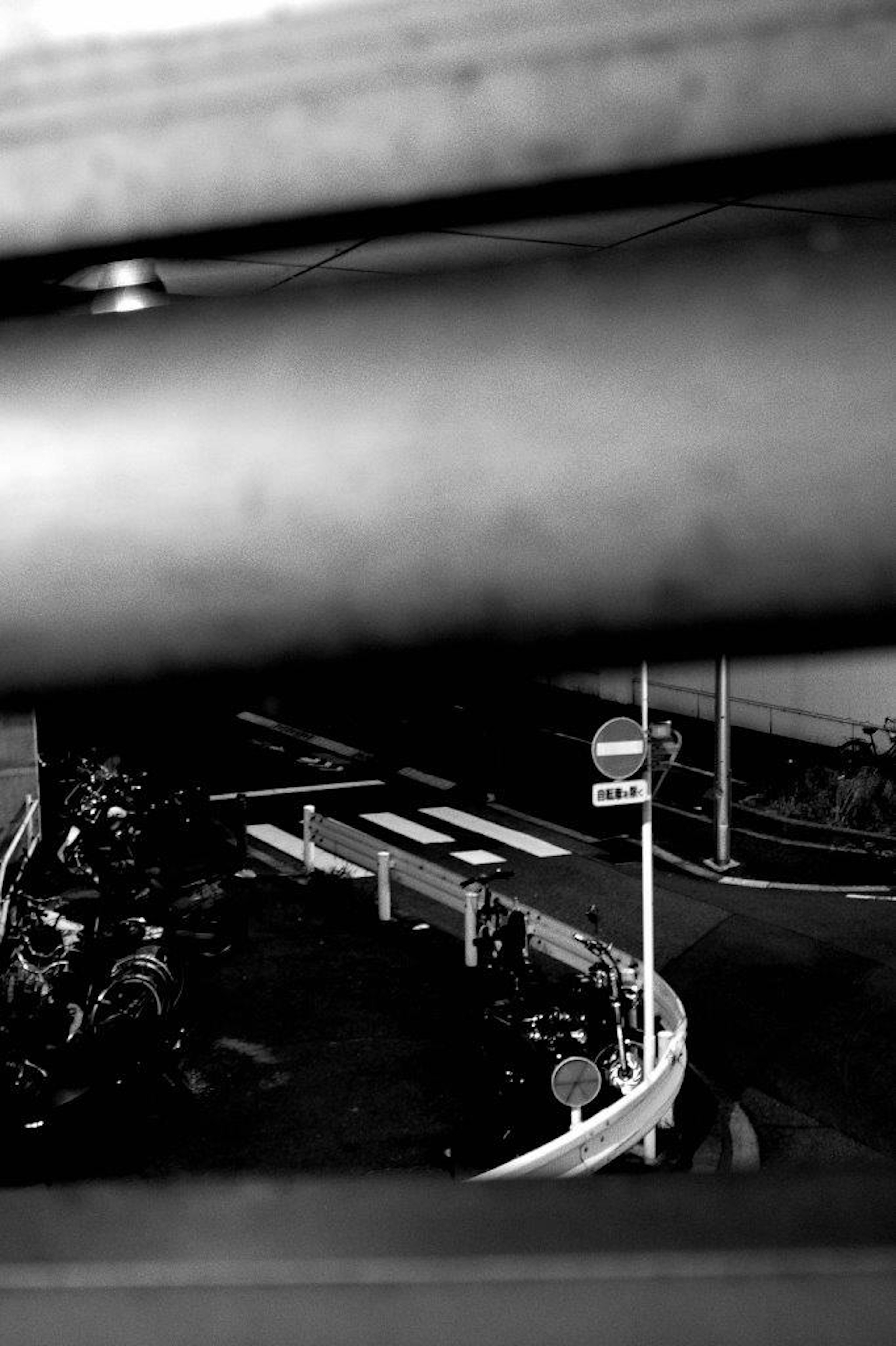 Black and white urban scene showing a winding road and a traffic signal