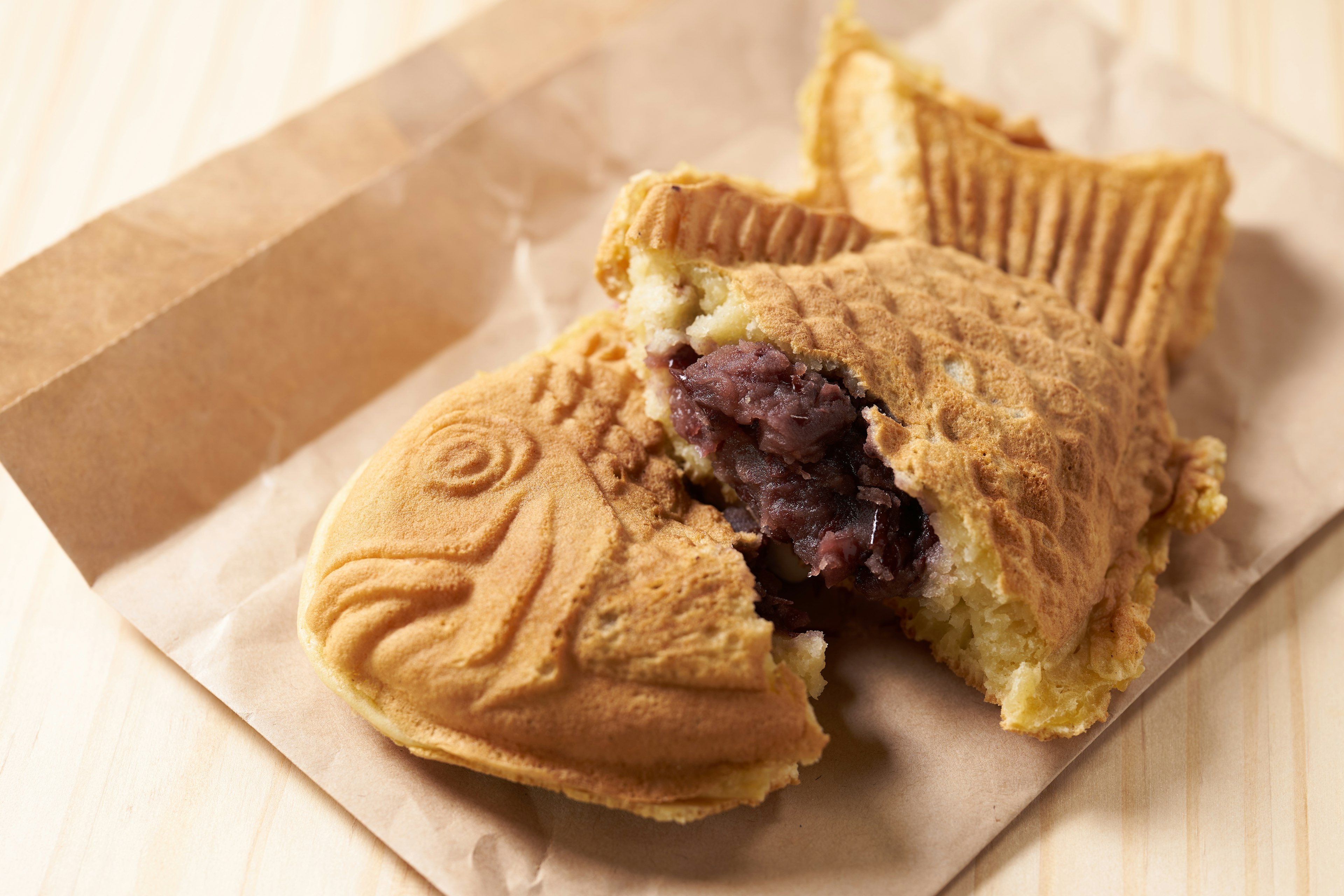 Makanan penutup Taiyaki berbentuk ikan dengan isian kacang merah yang sebagian pecah