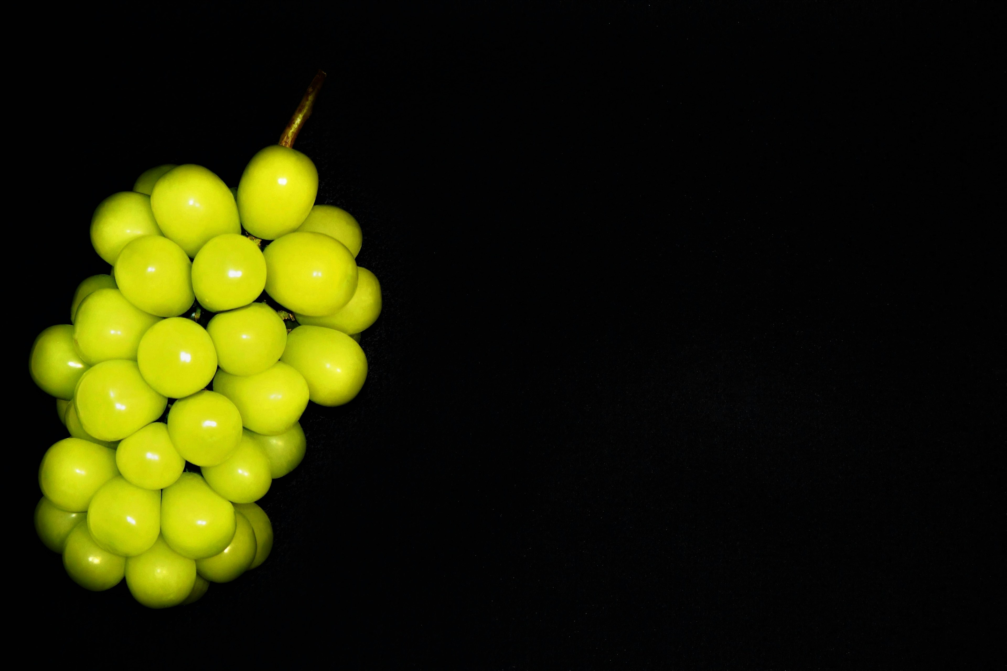 Un racimo de uvas verdes vibrantes sobre un fondo negro