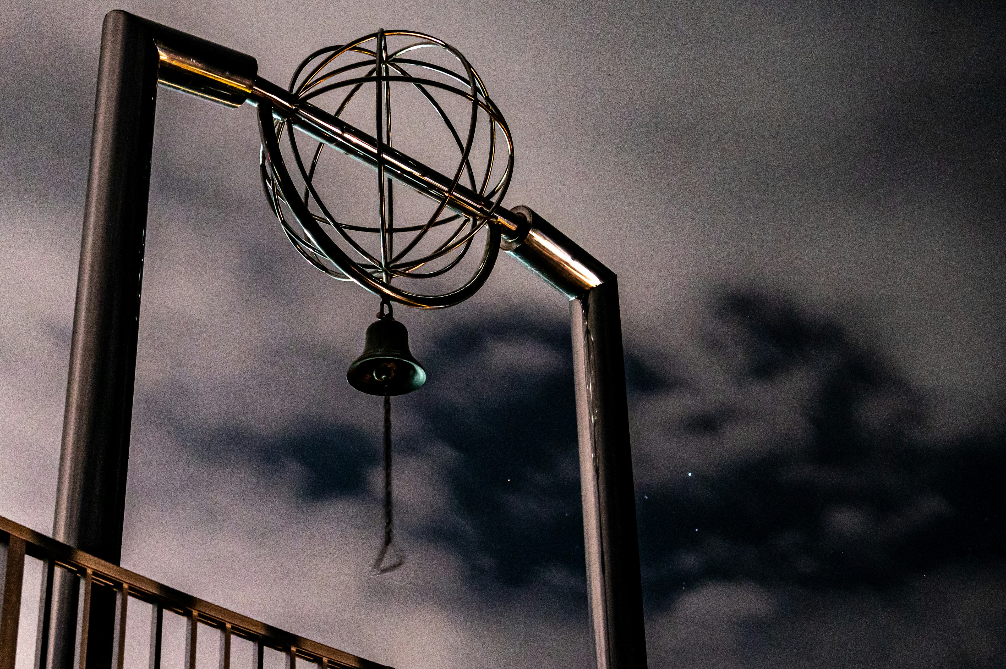 Foto einer Struktur mit einem silbernen Globus und einer hängenden Glocke