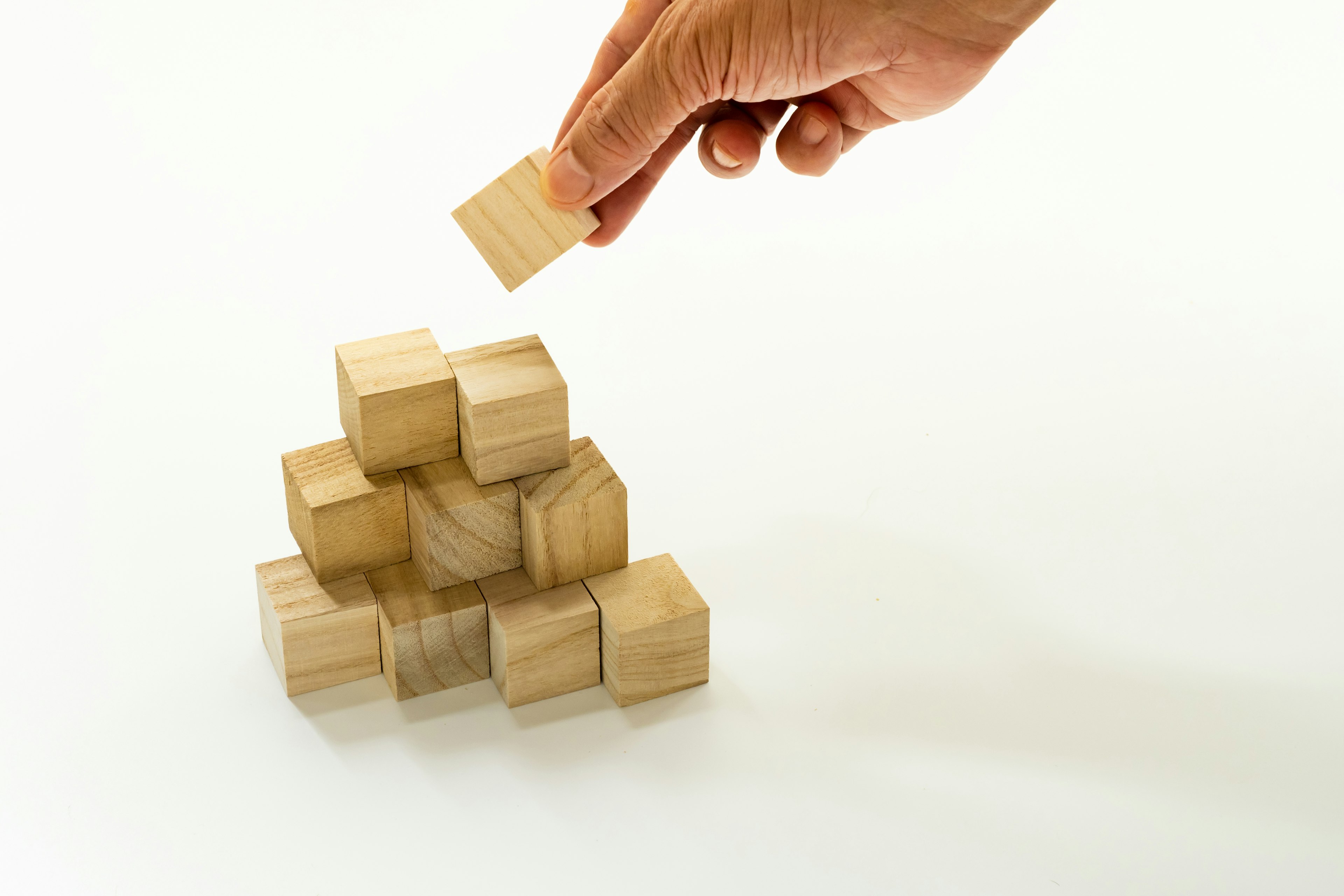 A hand placing a wooden block on a stack of blocks