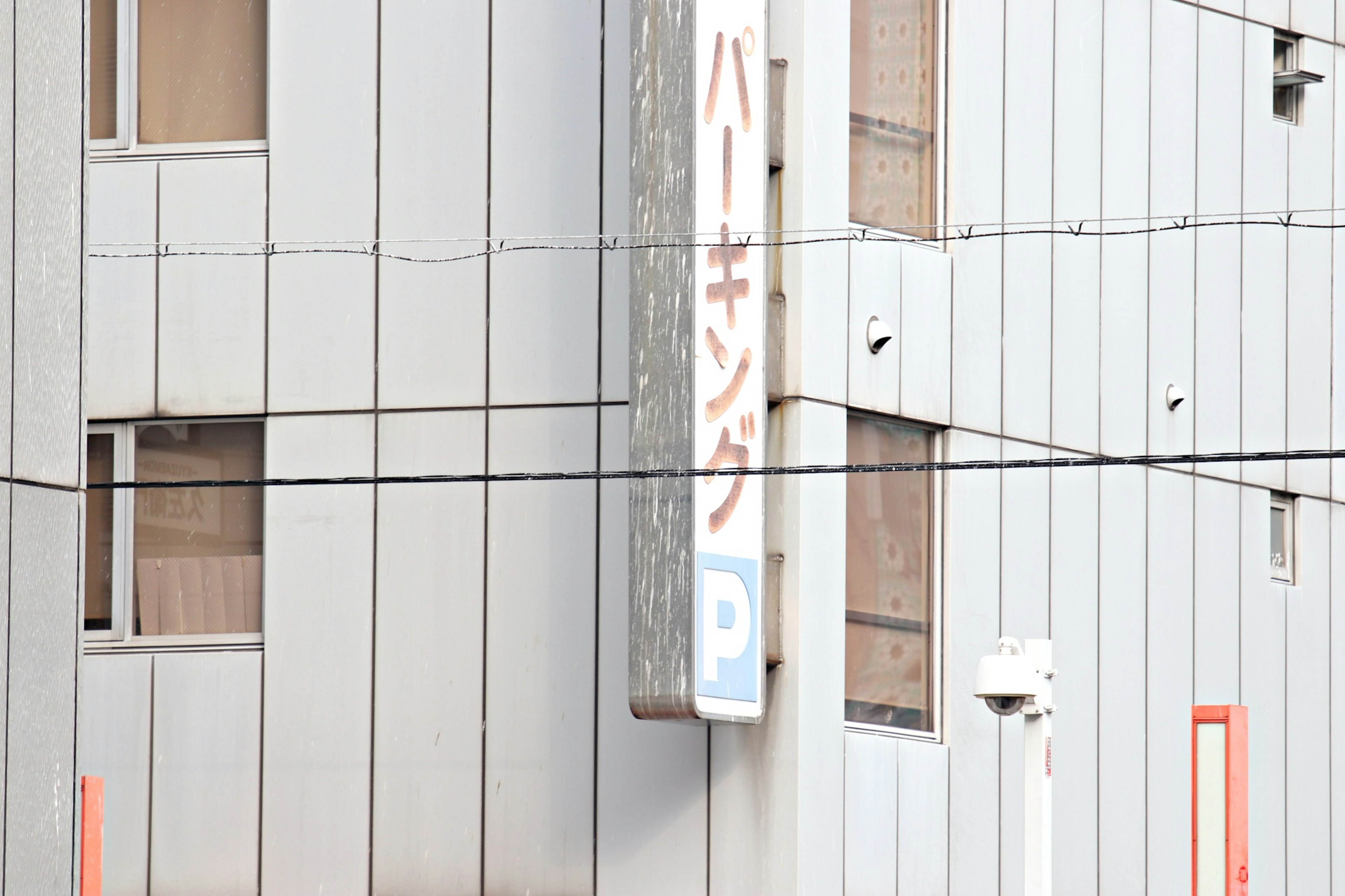 Parking sign mounted on the side of a gray building