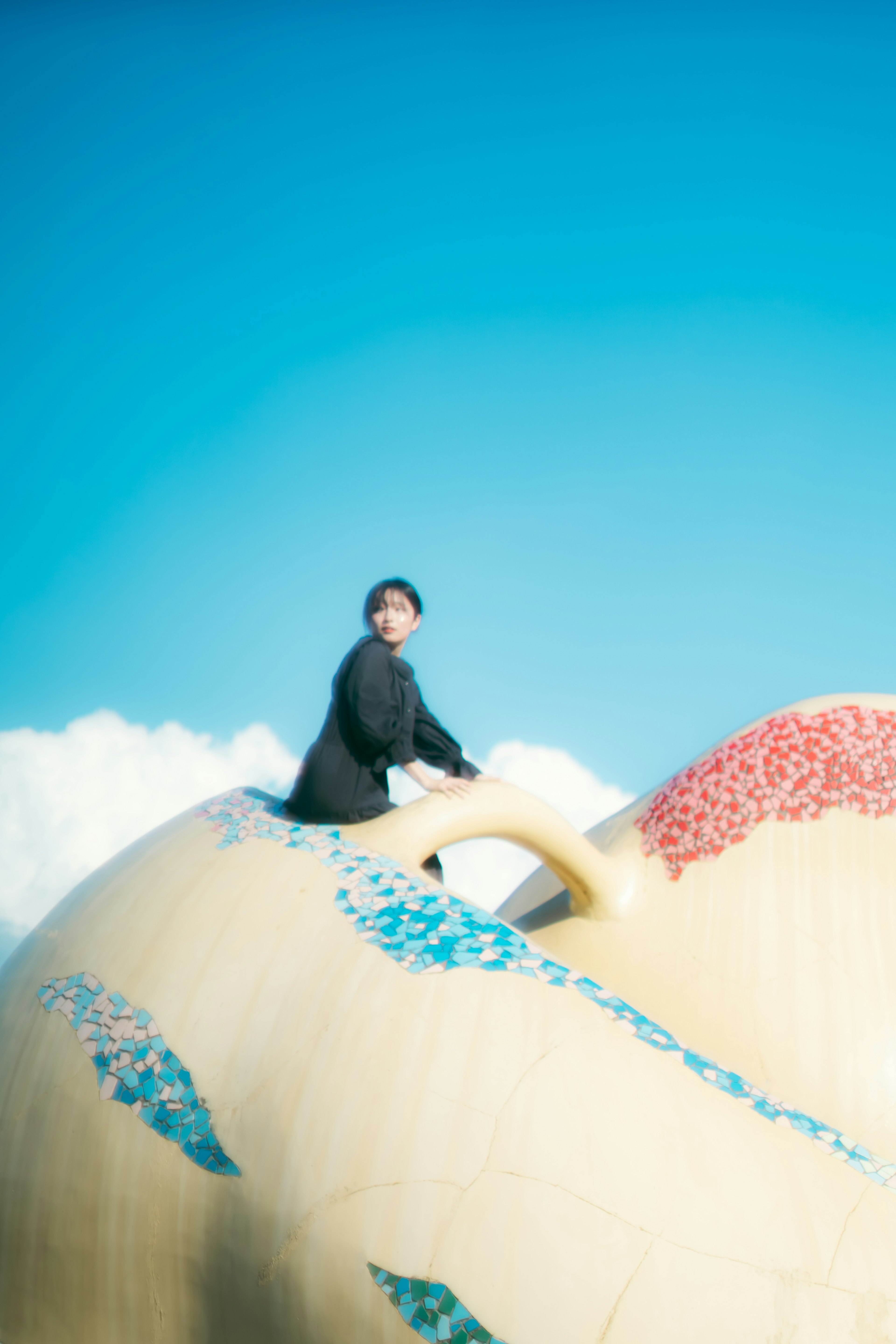 A person sitting on a colorful sculpture under a blue sky
