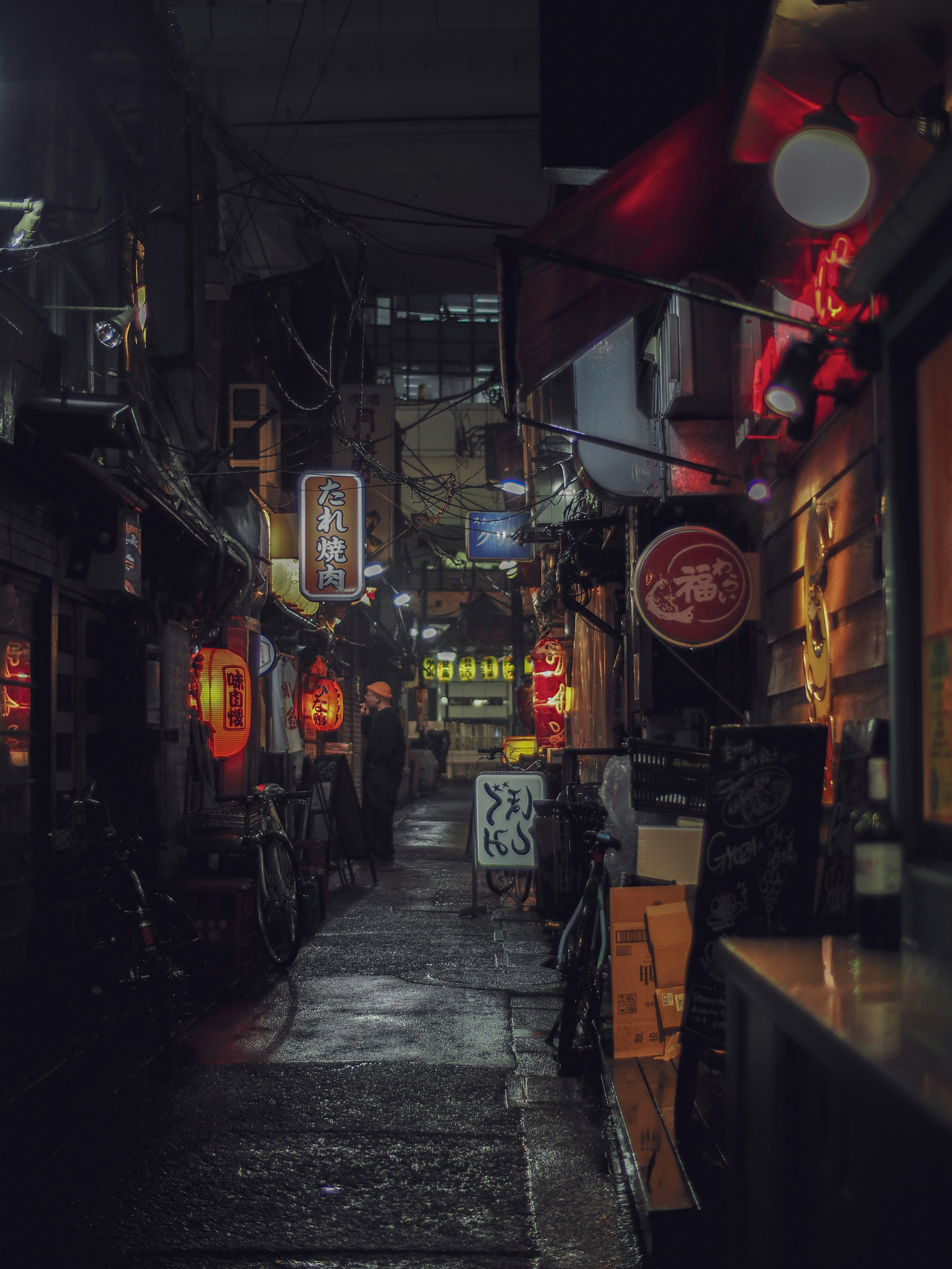 Ruelle étroite la nuit avec des enseignes au néon et des lanternes