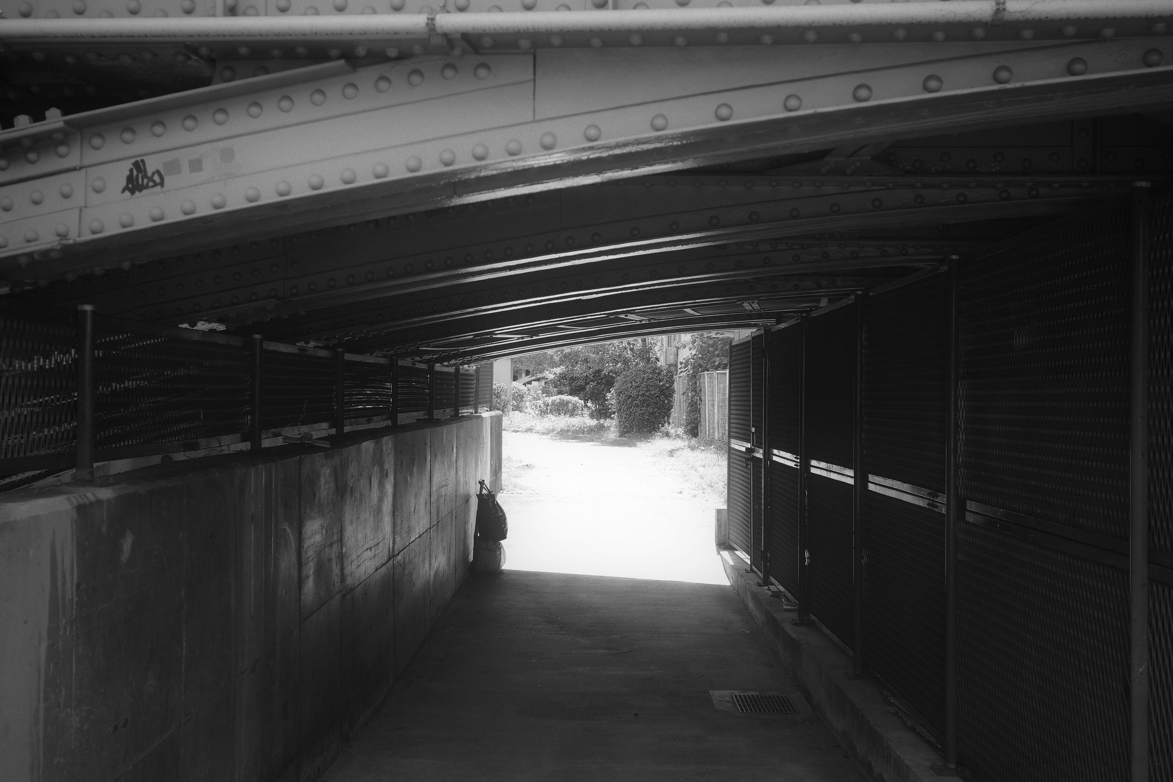 Monochrome image of an underground tunnel with a visible exit