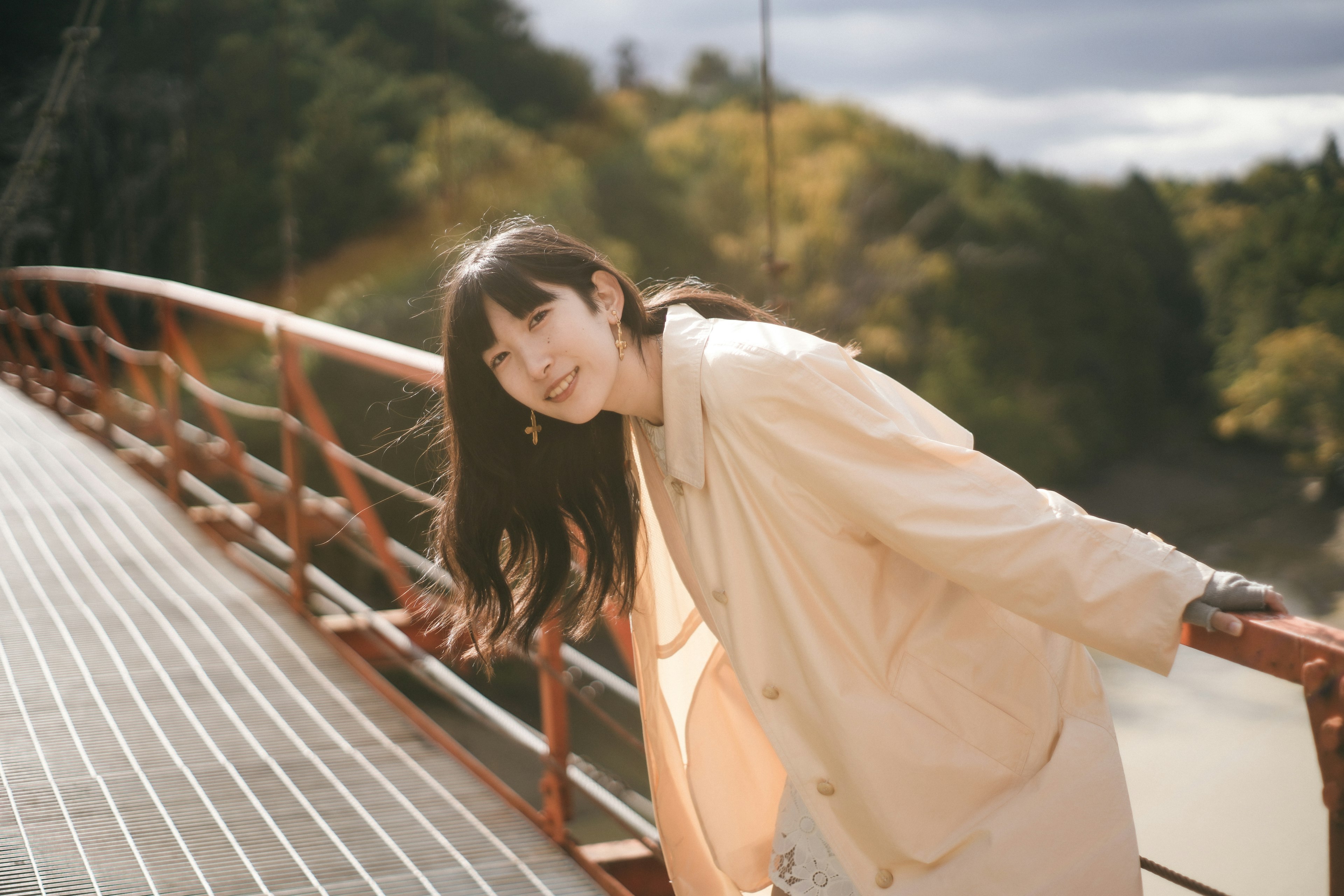 橋の上に立つ女性の微笑む姿と秋の風景