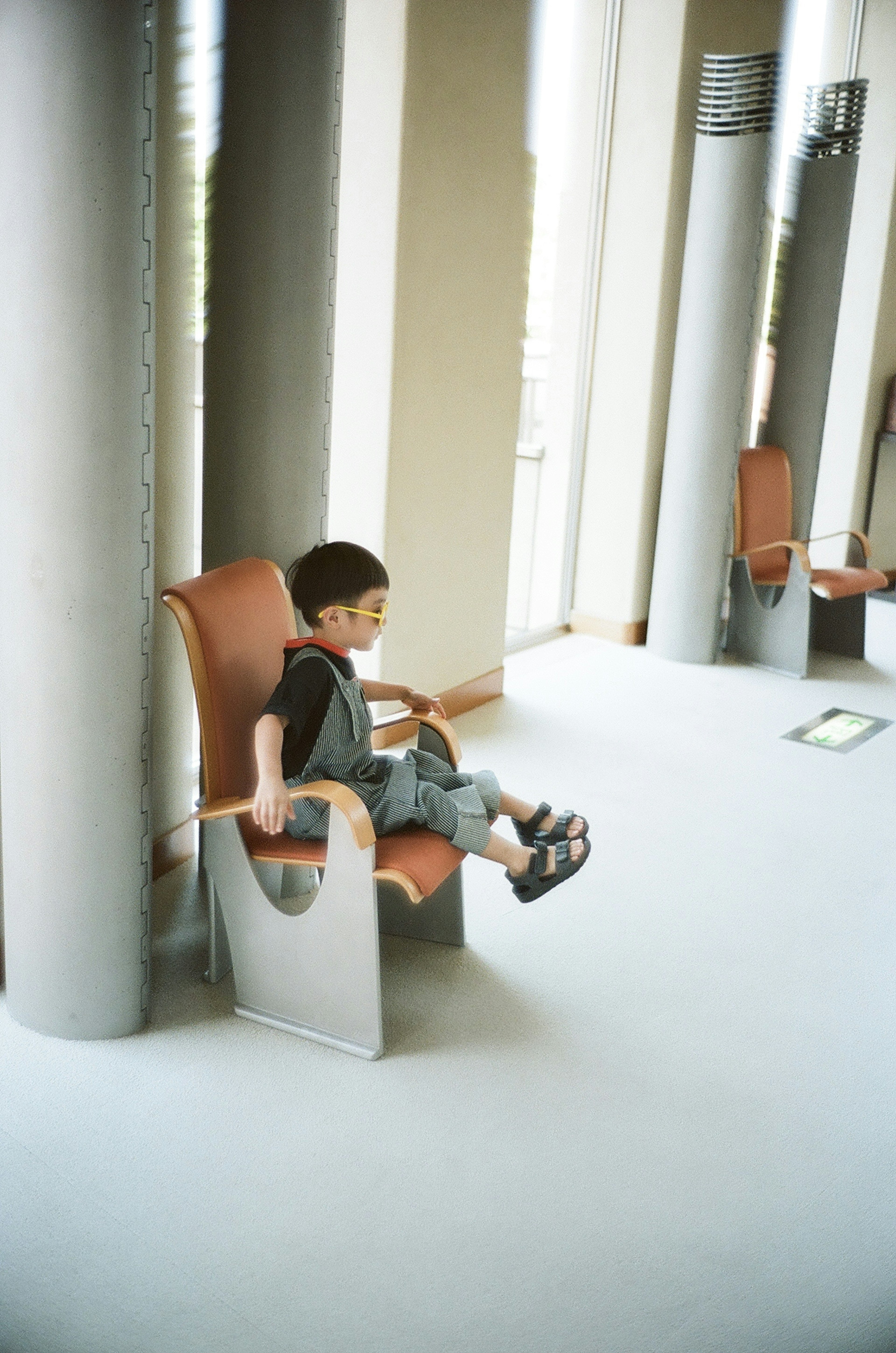 A child sitting in a modern chair in an indoor setting