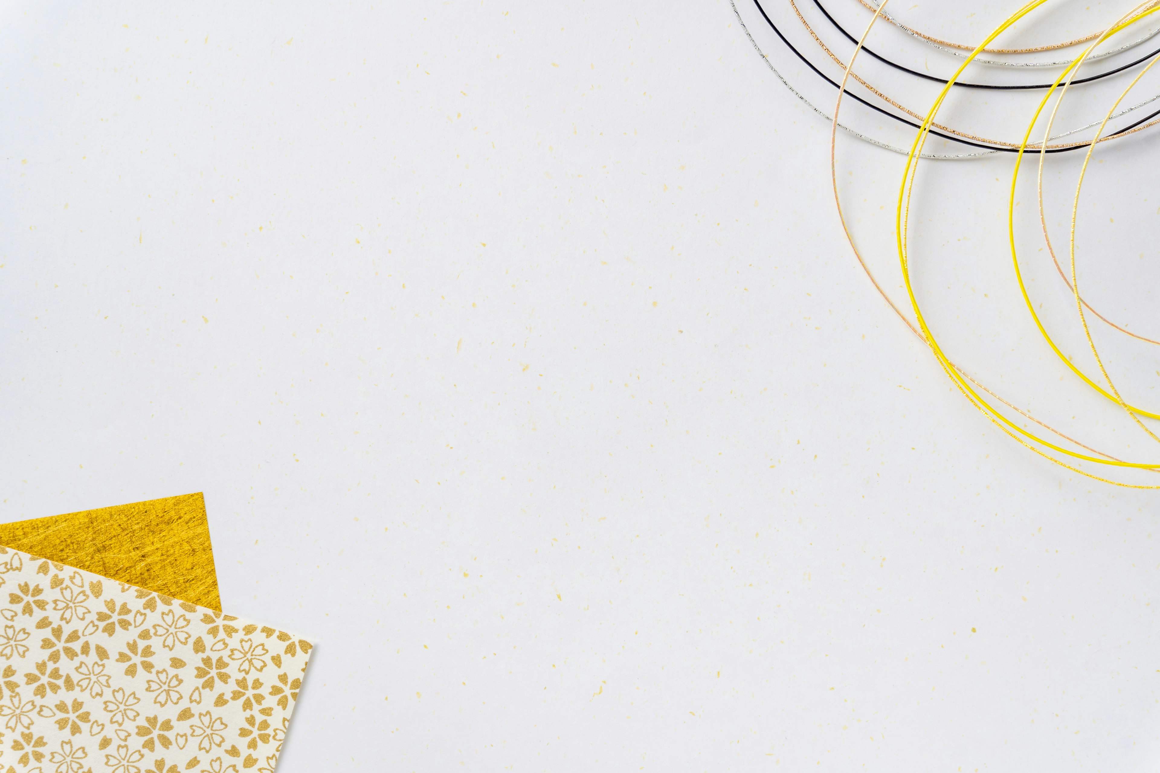 A white background featuring decorative yellow paper and golden wire