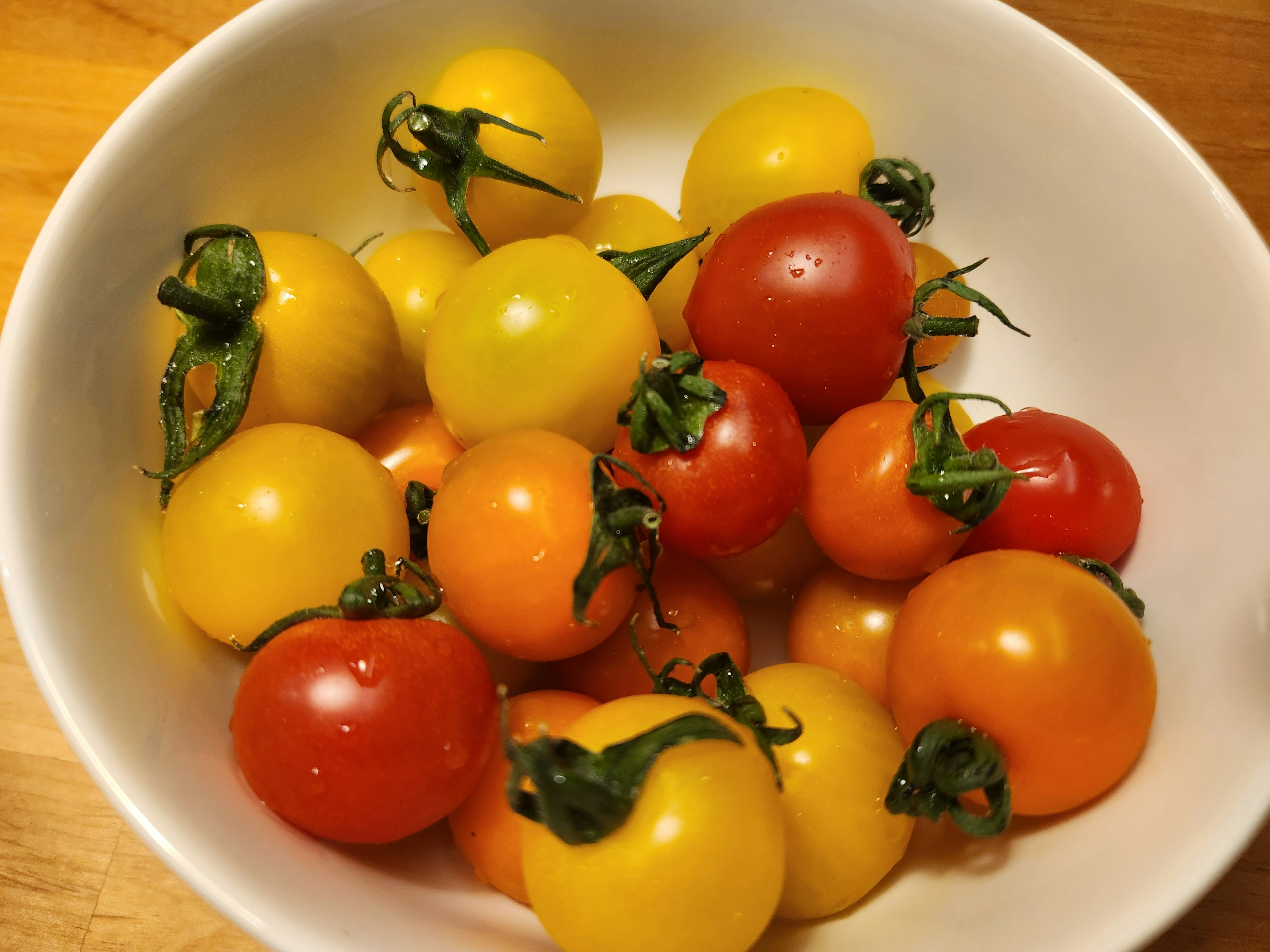 A bowl filled with colorful cherry tomatoes in various shades