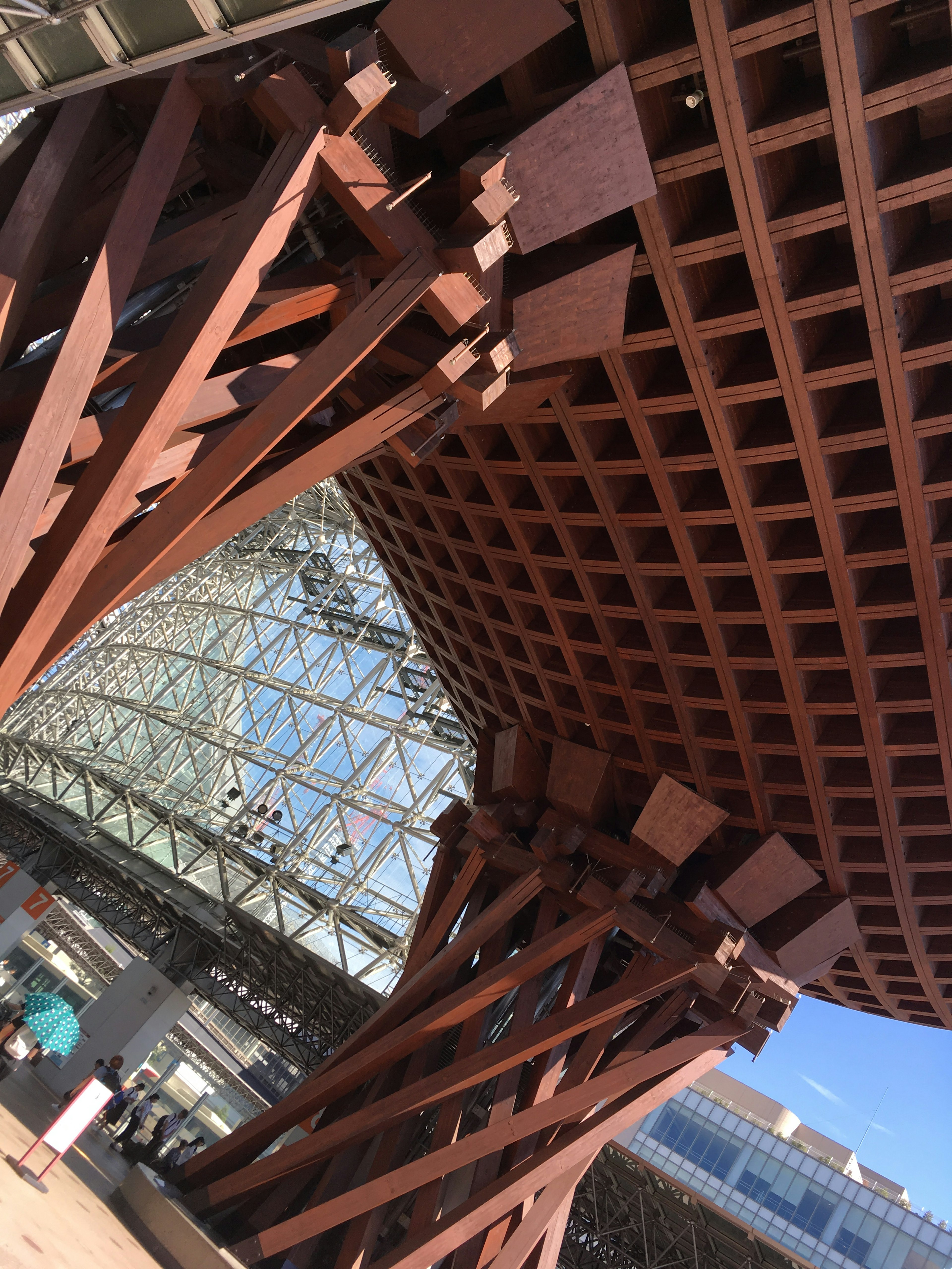 Vista interior de un edificio con una estructura de madera distintiva y una fachada de vidrio