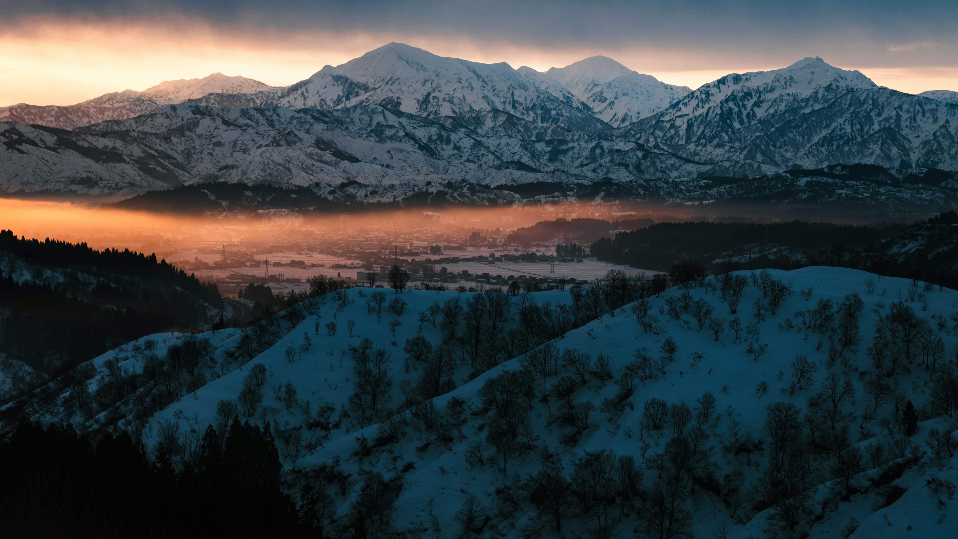 雪覆蓋的山脈與黎明時分的霧氣彌漫的山谷