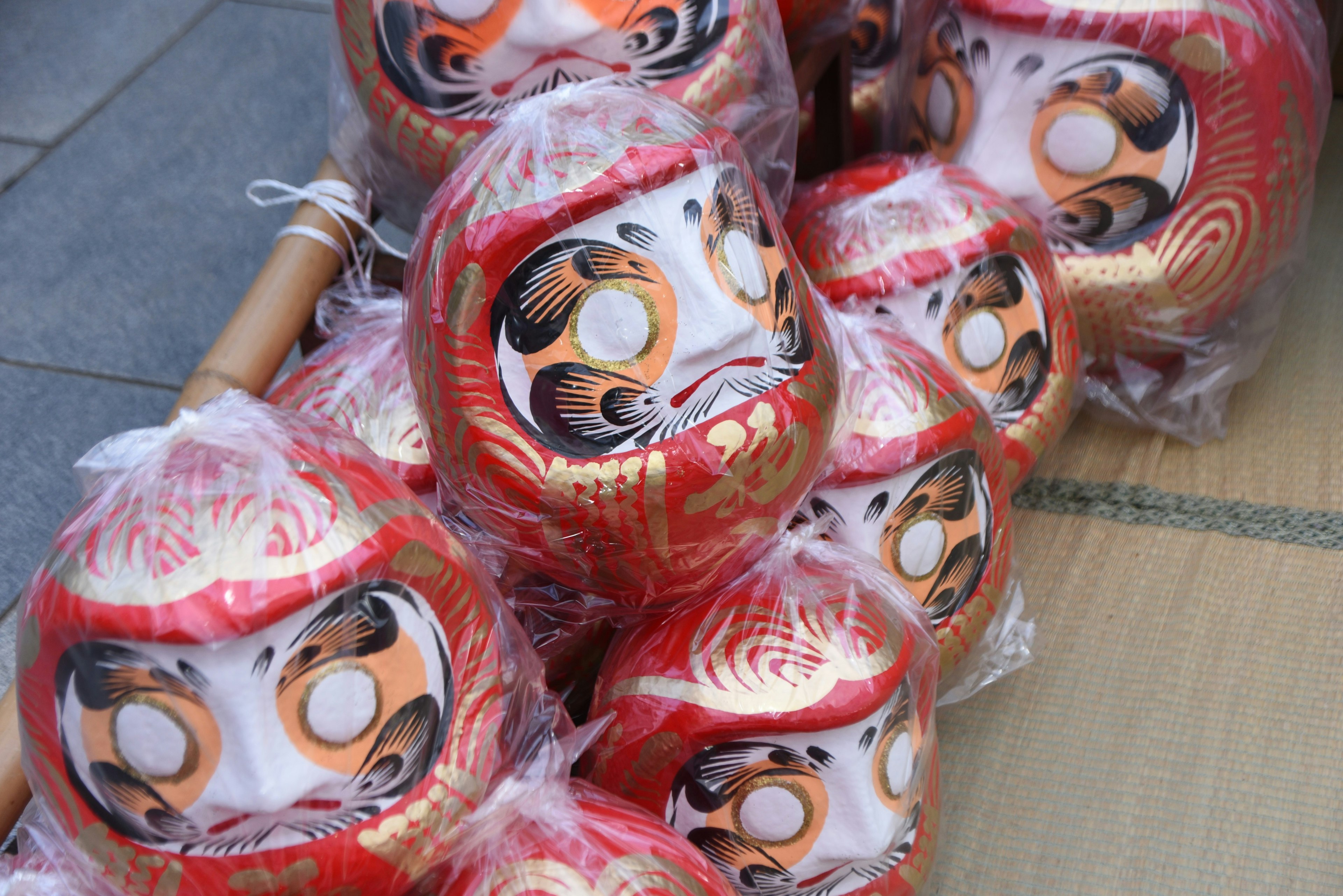 Eine Sammlung roter Daruma-Puppen, die in Plastik eingewickelt sind