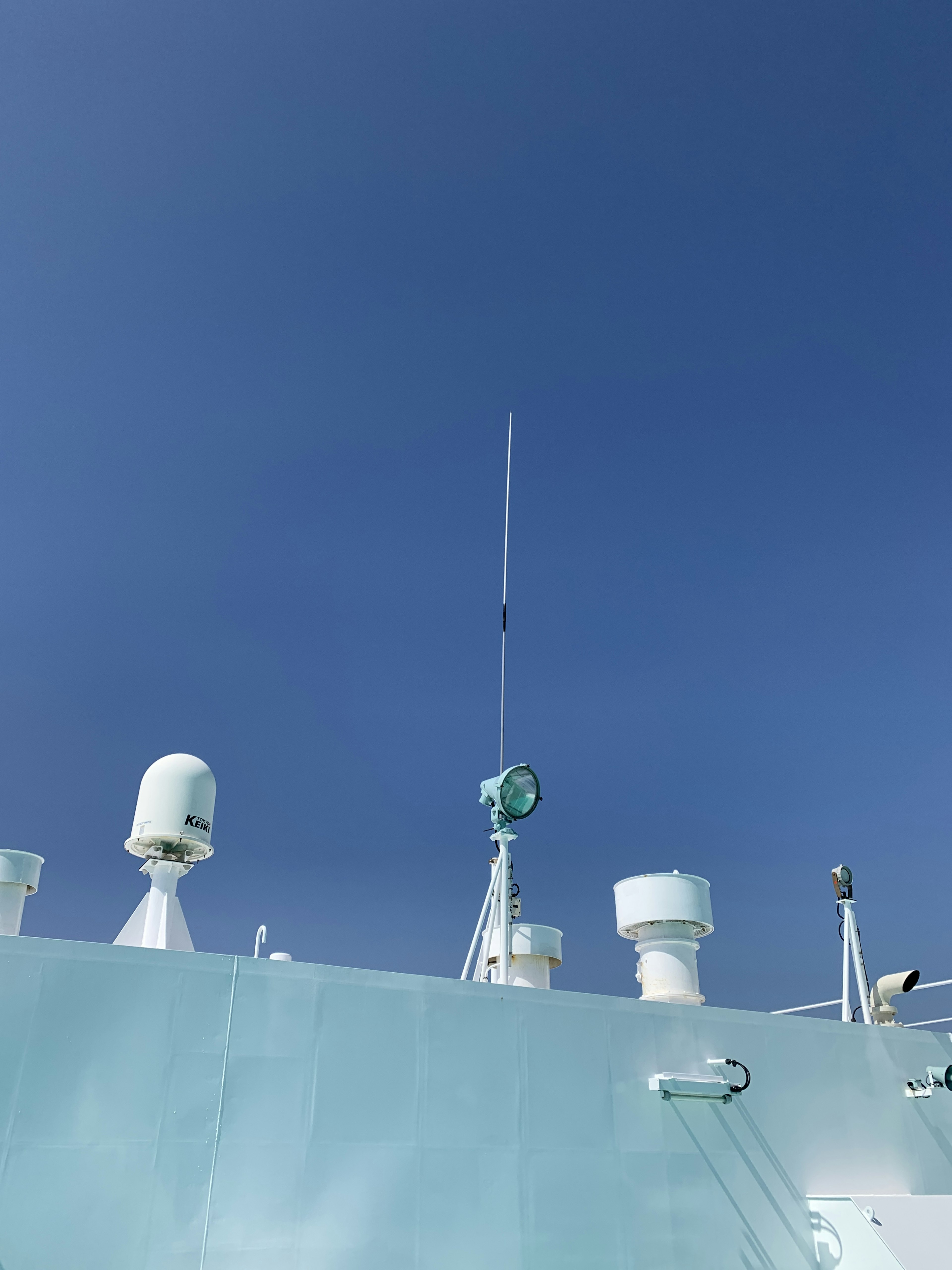 Upper structure and antenna of a ship against a blue sky