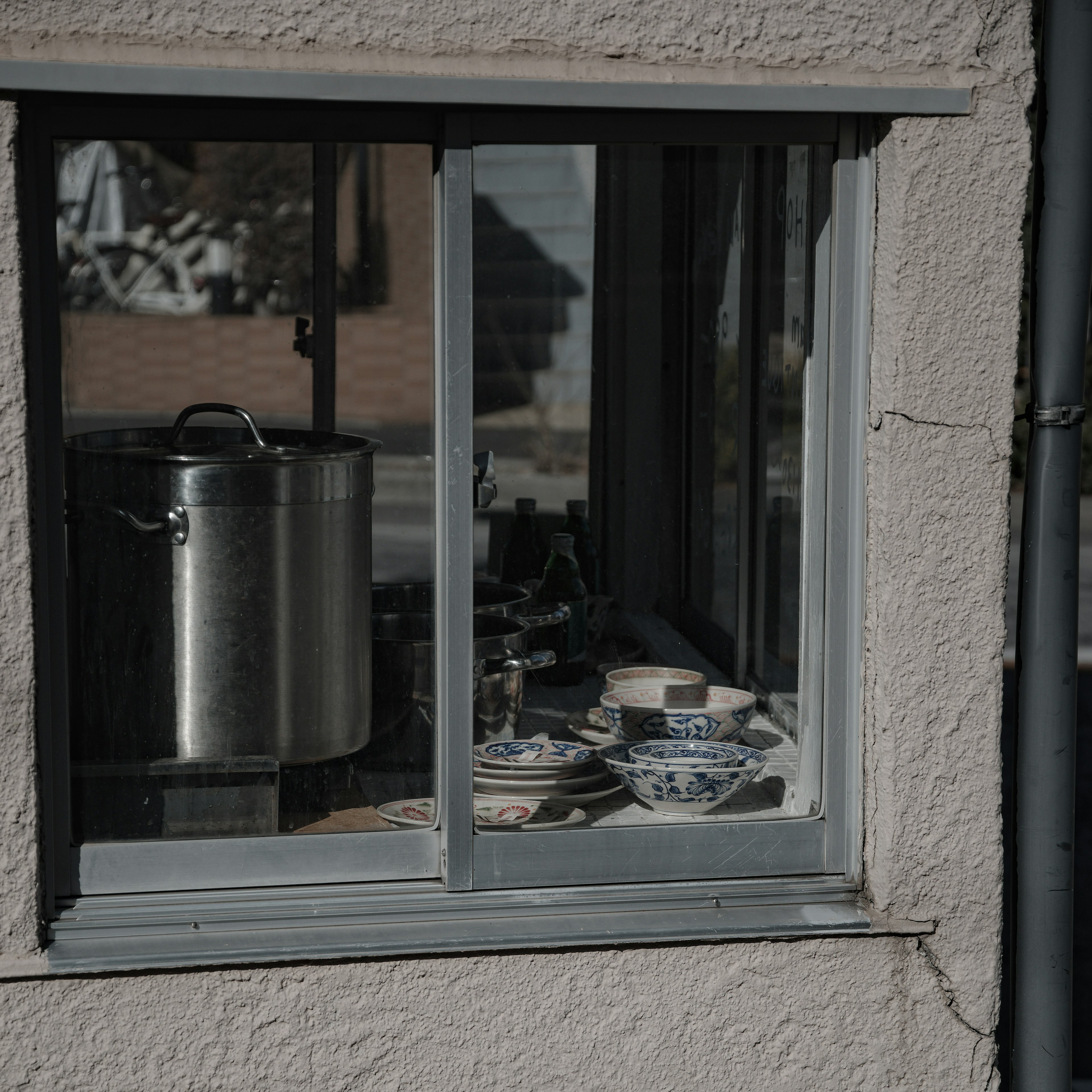 Blick auf eine Küche durch ein Fenster mit Töpfen und Tellern