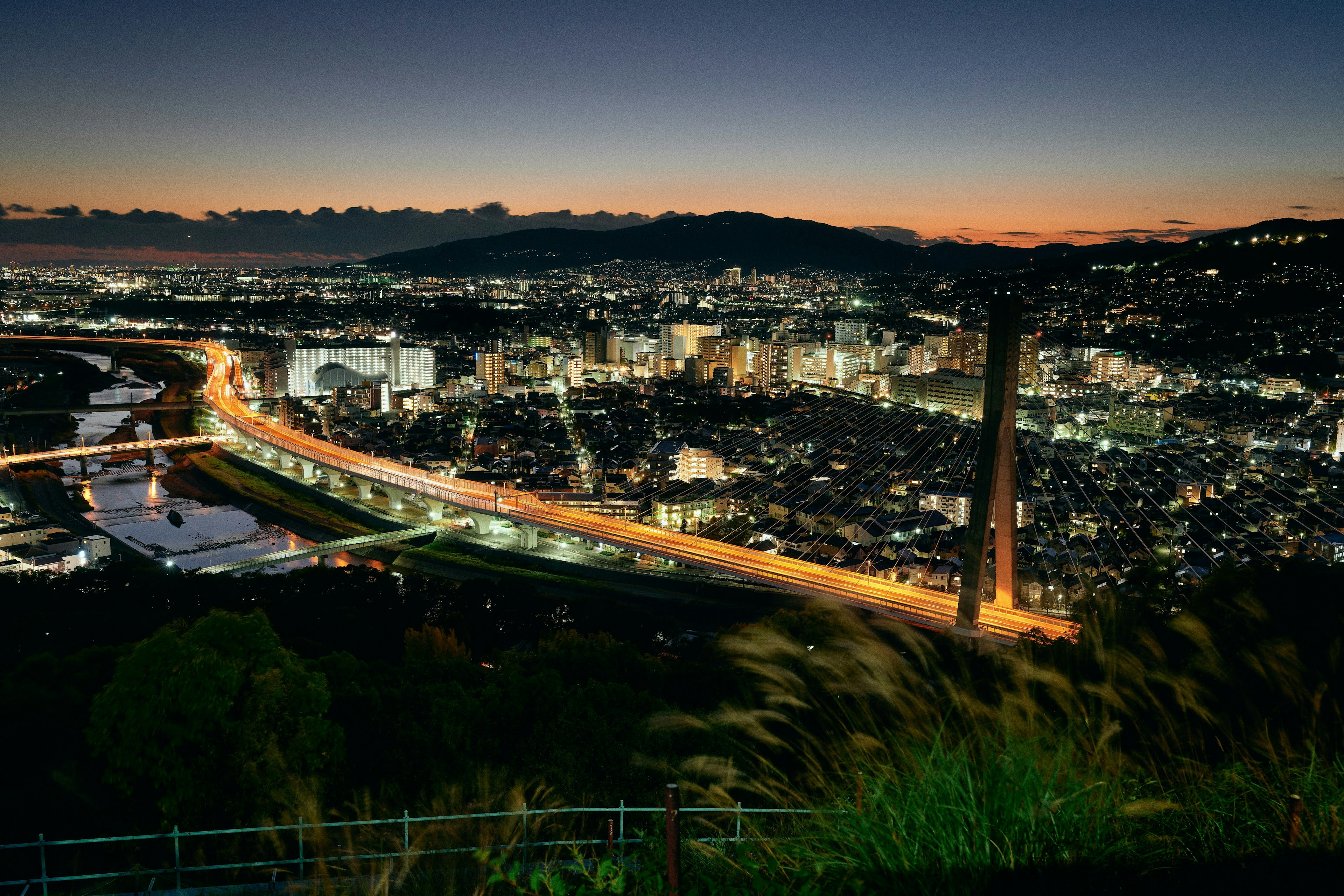 Vue nocturne d'un paysage urbain avec une rivière et des montagnes au loin