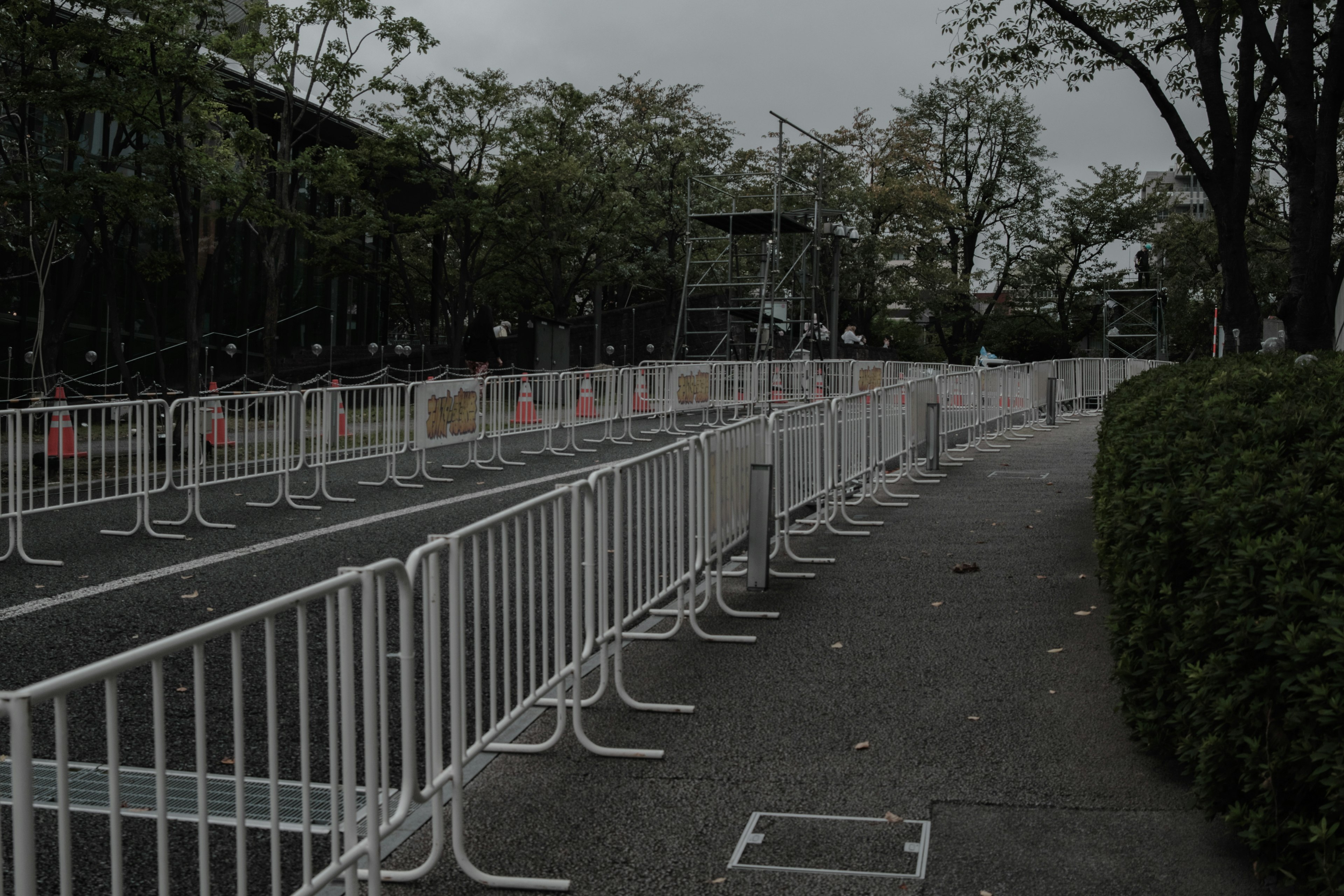 Scene of white barriers lining a street with green shrubbery