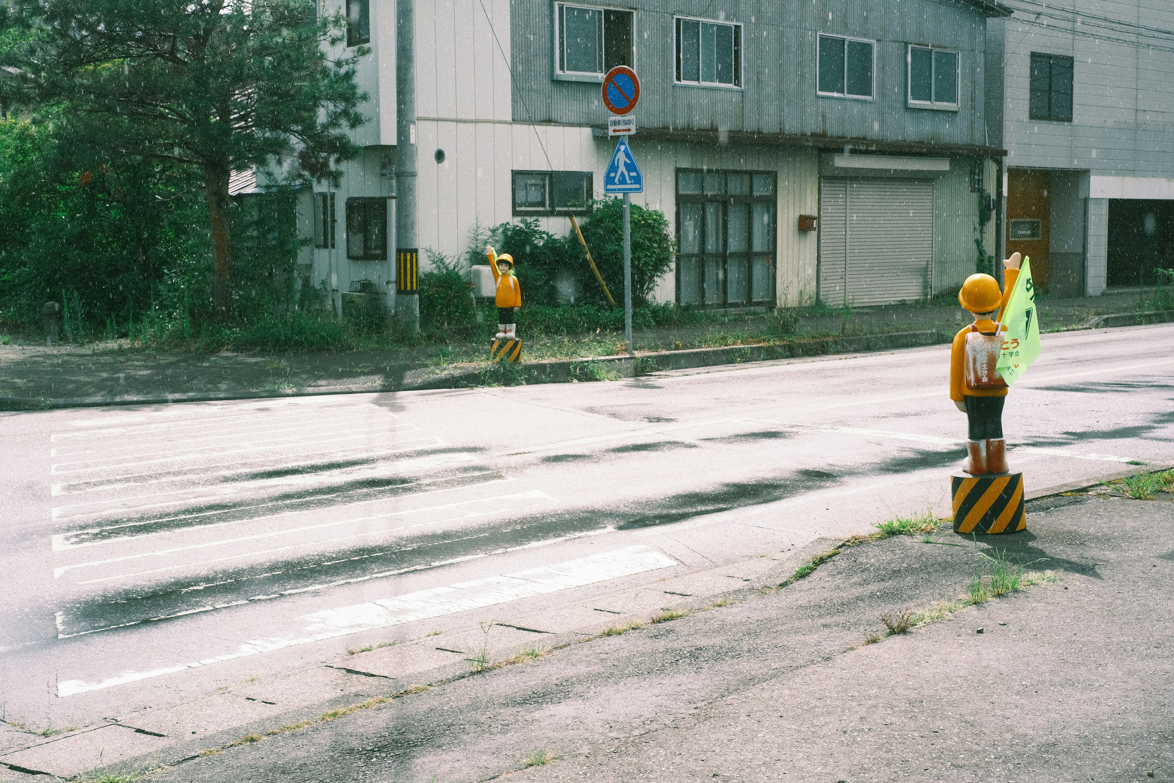 Dos trabajadores de construcción sosteniendo señales de tráfico en una carretera mojada