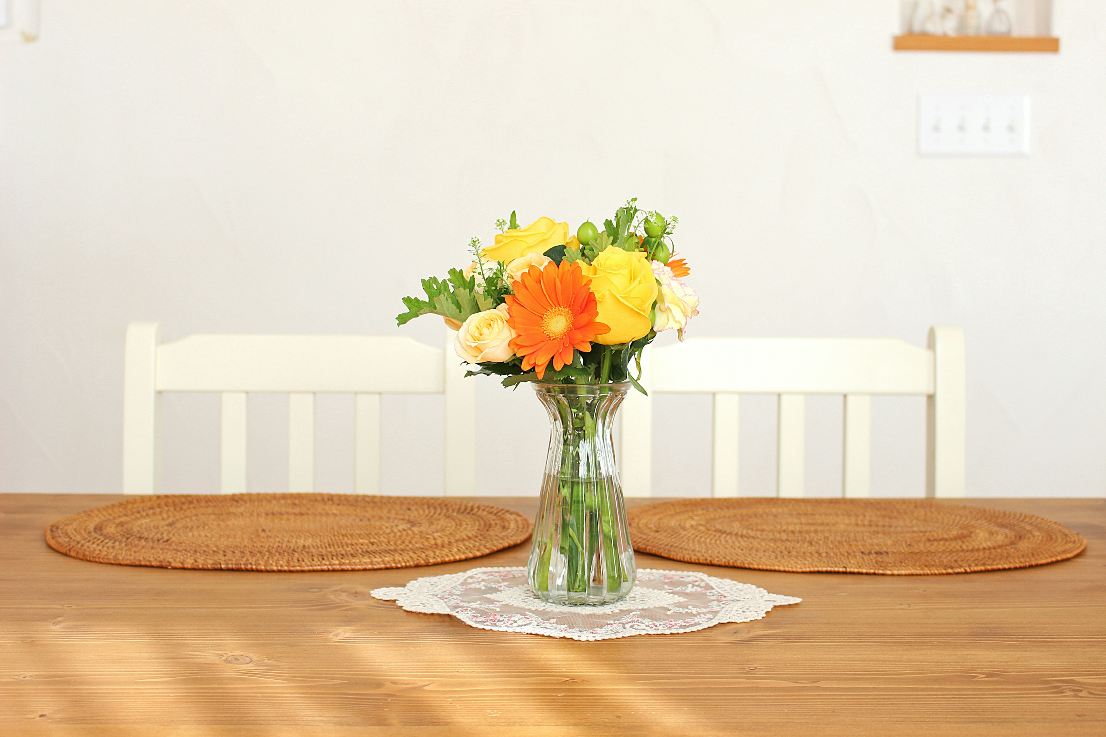 A simple dining scene featuring a vase of colorful flowers on a wooden table