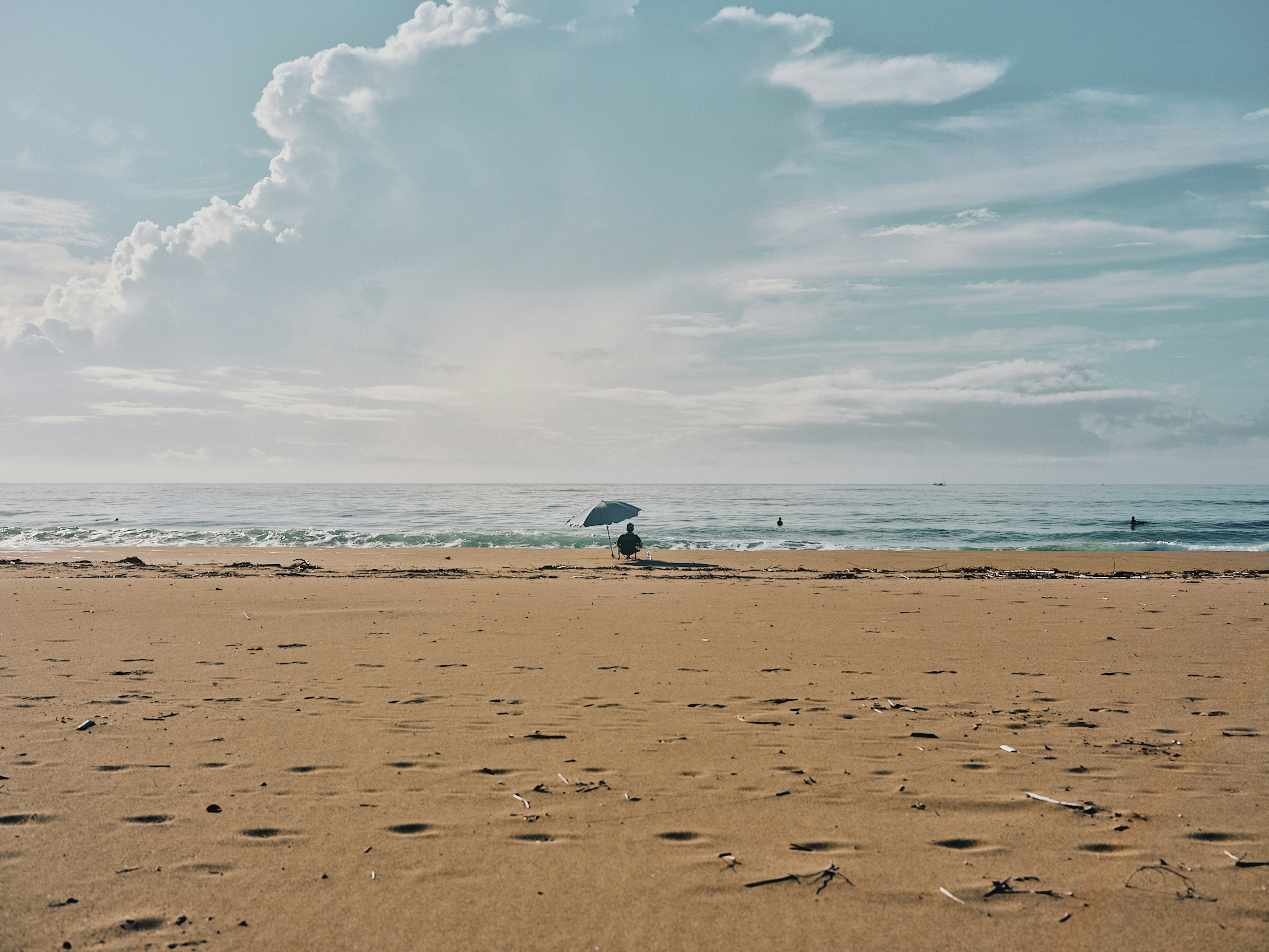 ชายหาดกว้างพร้อมคลื่นนุ่มและท้องฟ้าสีฟ้ากับเมฆขาว