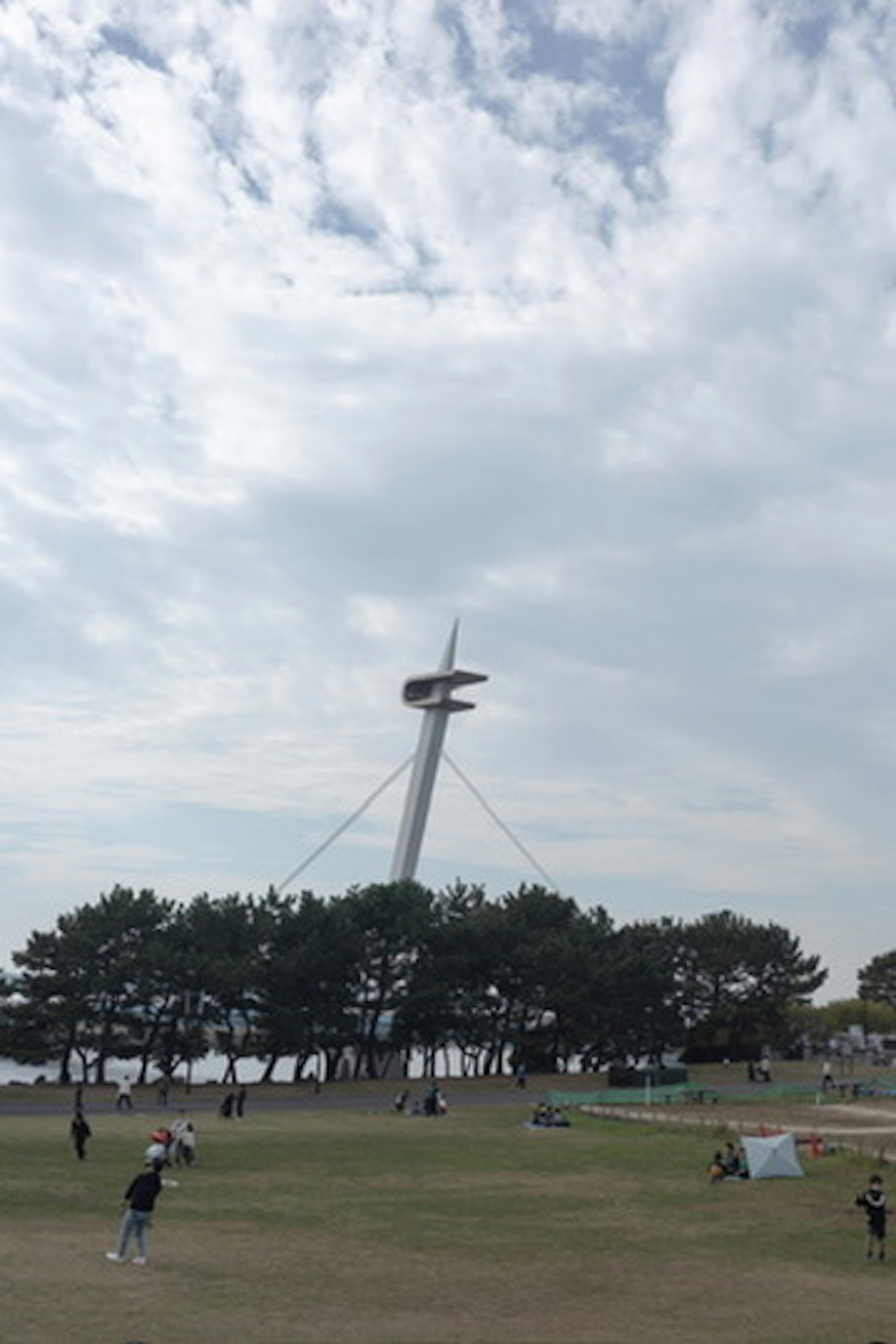 Tall tower with a rotating structure behind green trees