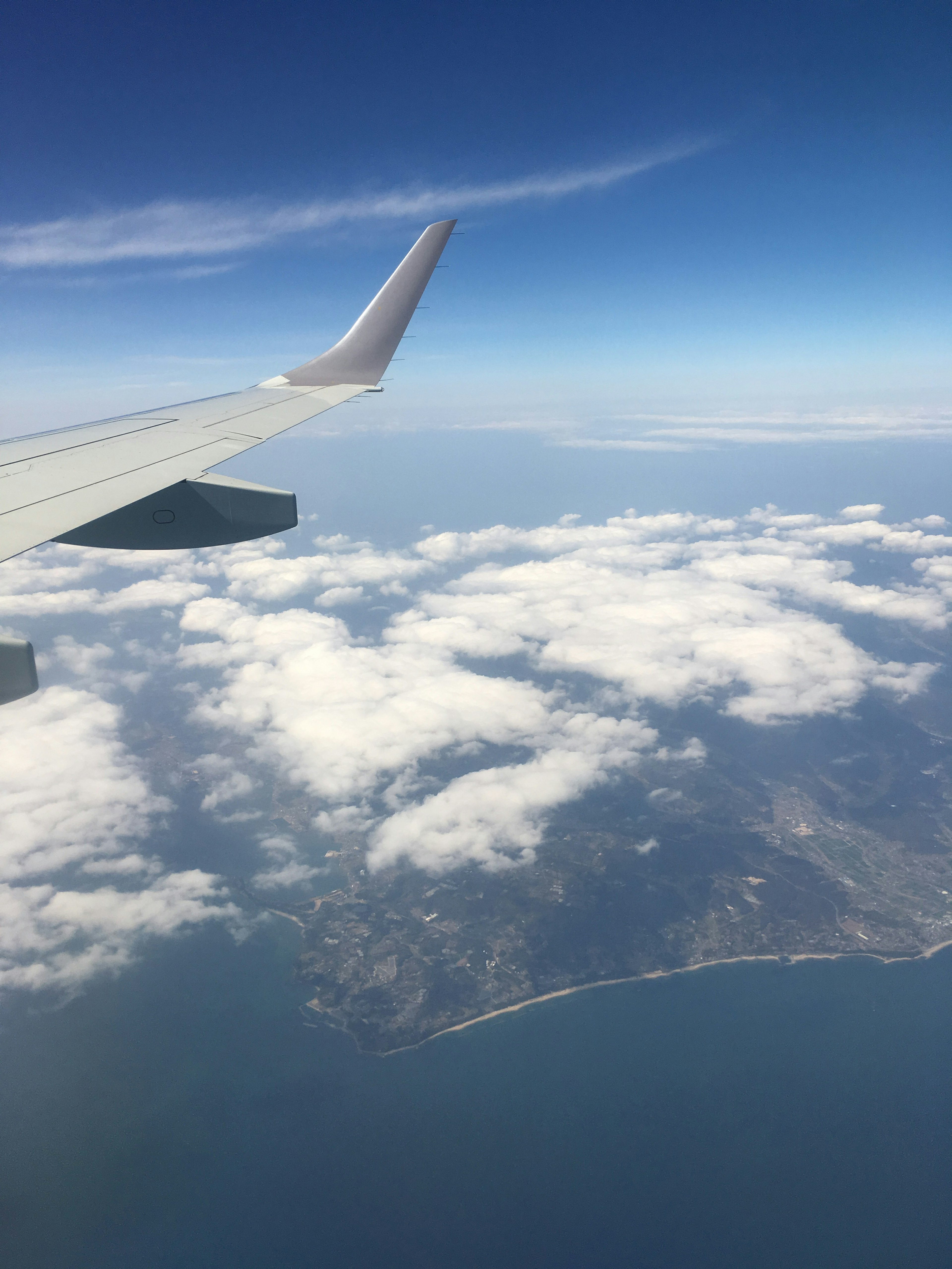 Aile d'avion au-dessus des nuages avec une côte visible