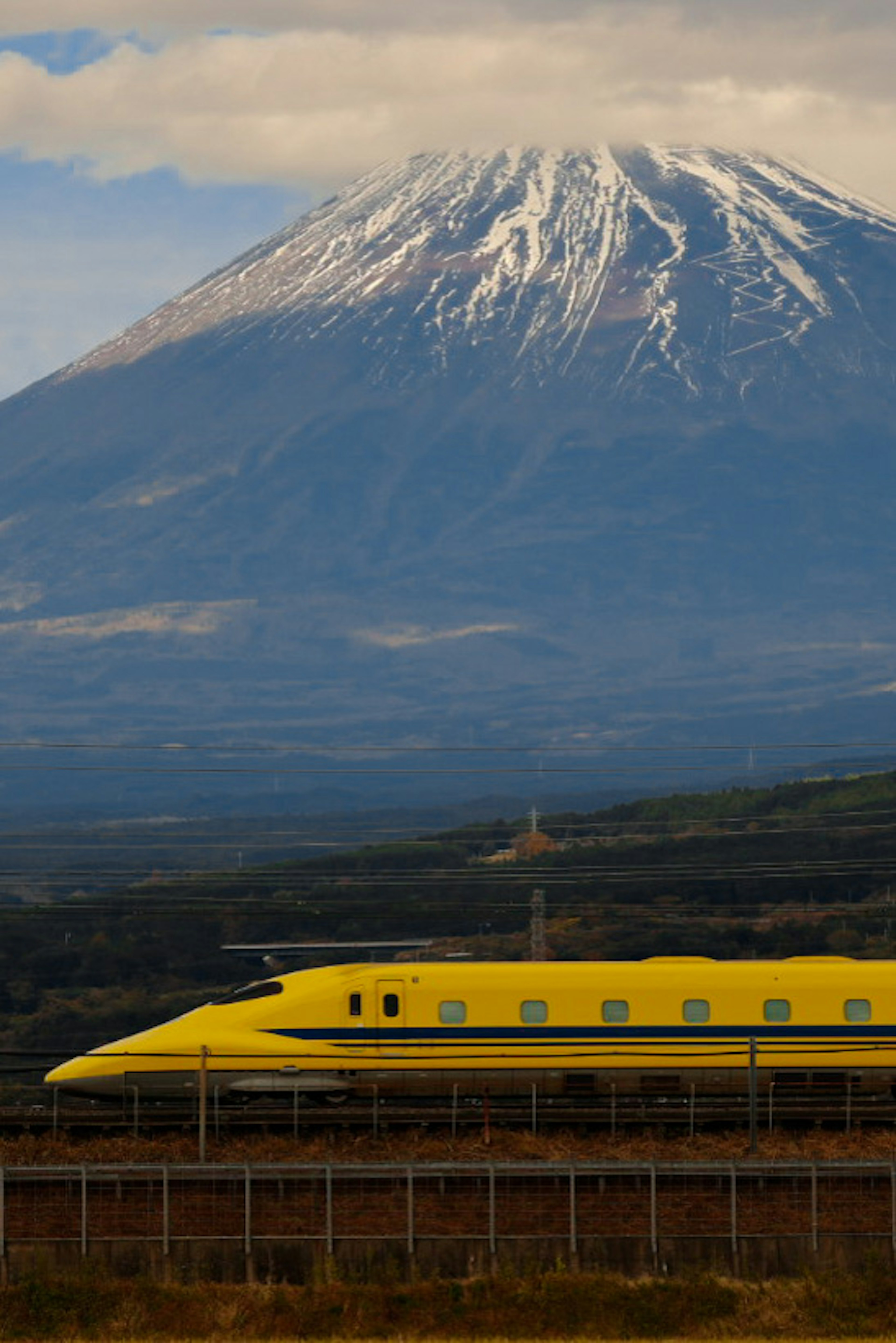 富士山の背景に黄色い新幹線が走る風景